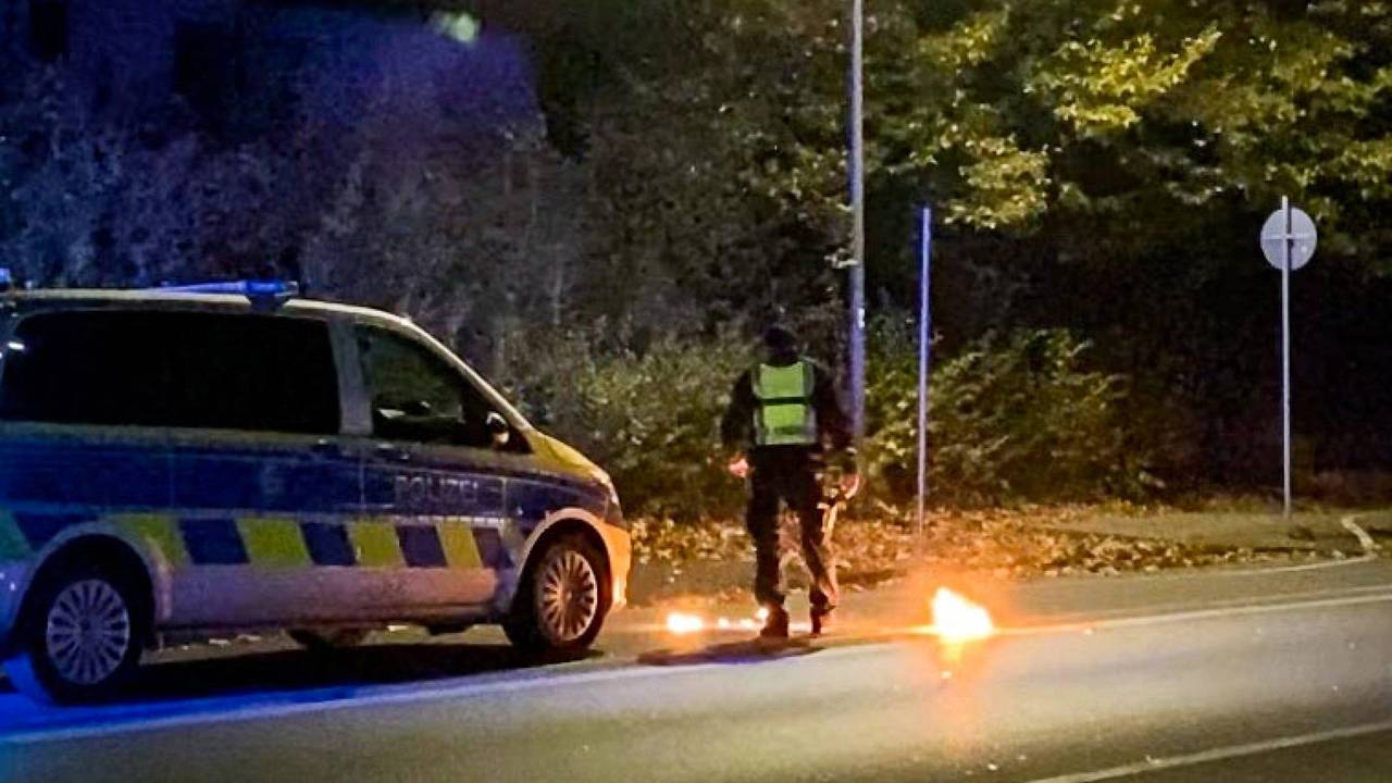 Ein Polizist steht am 4. November 2022 bei dem Feuer vor einem Streifenwagen. Bei einem Treffen der Tuning- und Raserszene an der A42 in Castrop-Rauxel (Kreis Recklinghausen) ist ein Mensch durch einen Knallkörper verletzt worden.