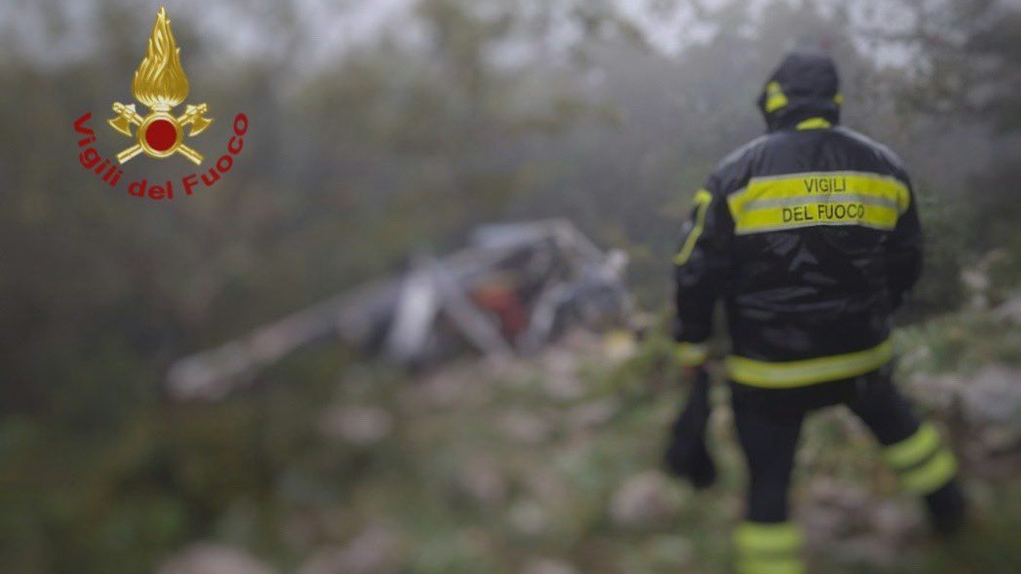 Ein Feuerwehrmann steht vor einem Hubschrauberwrack.