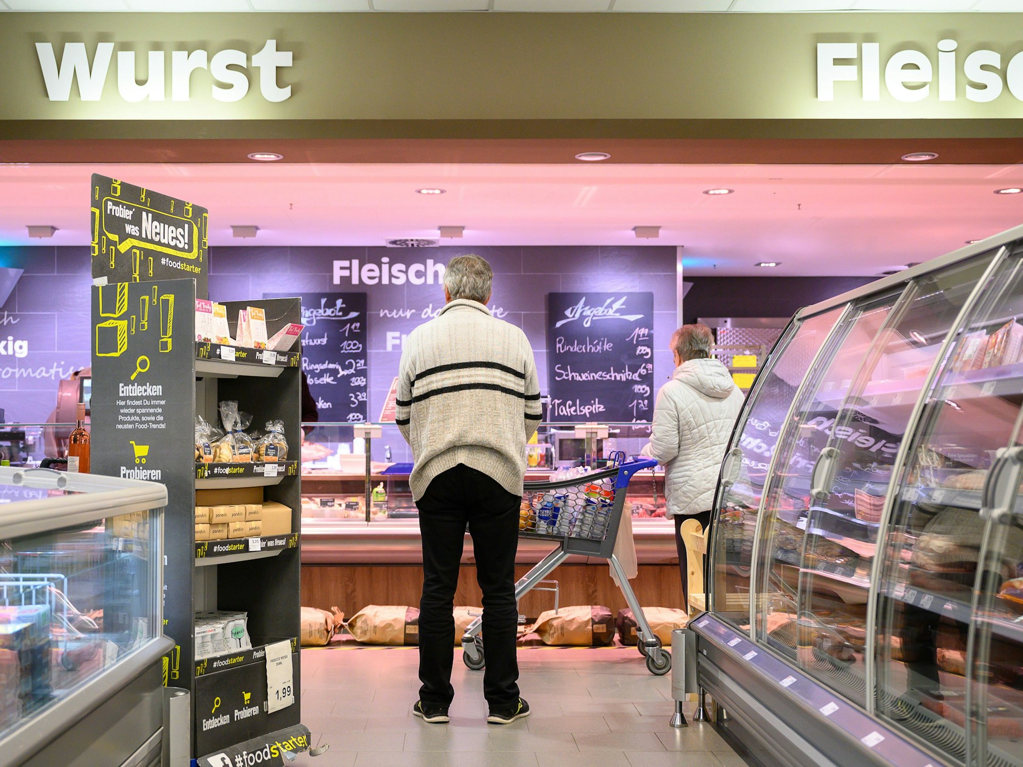 Kunden stehen in einer Edeka-Filiale vor der Fleischtheke.