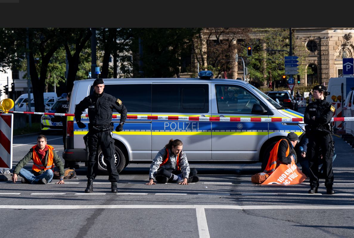 Klimaaktivisten kleben sich auf die Straße. Die Polizei sperrt den Bereich ab.