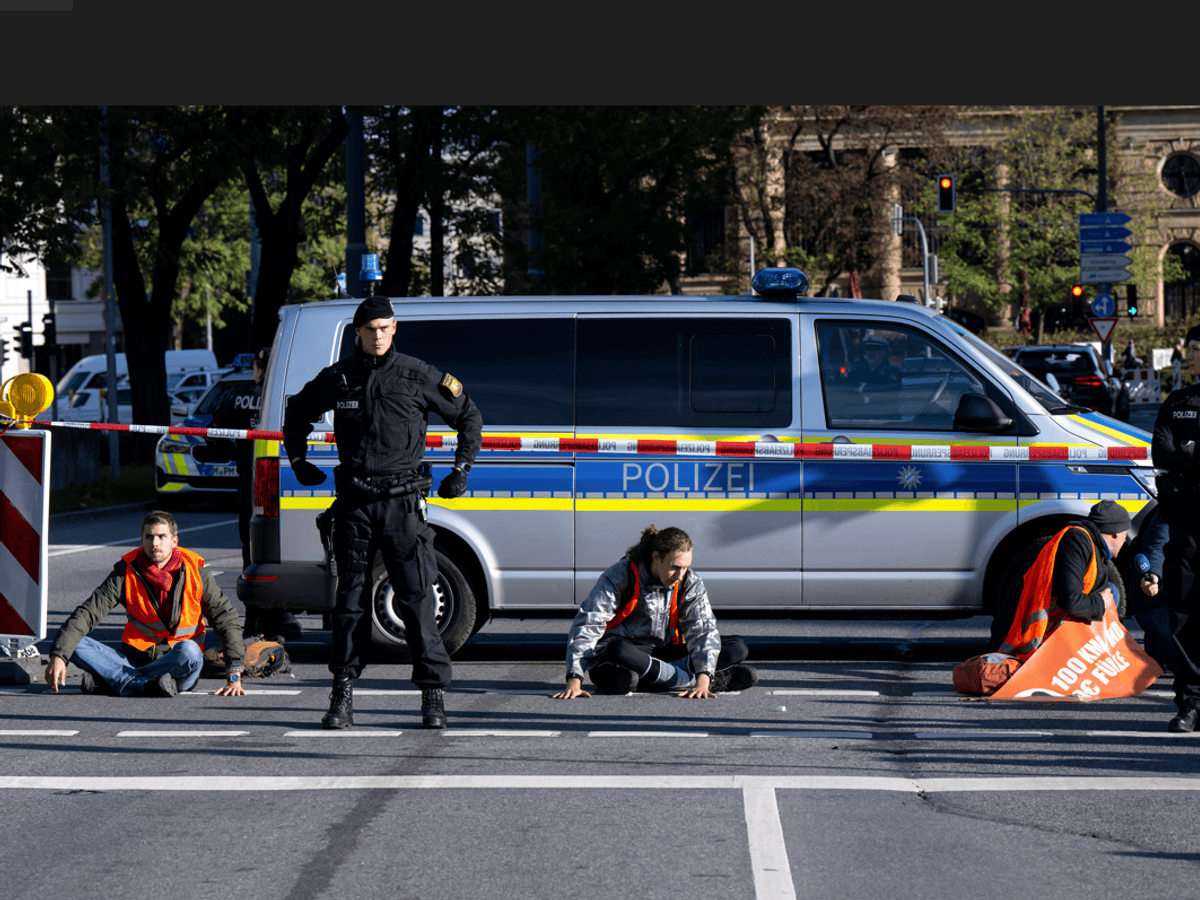 Klimaaktivisten kleben sich auf die Straße. Die Polizei sperrt den Bereich ab.