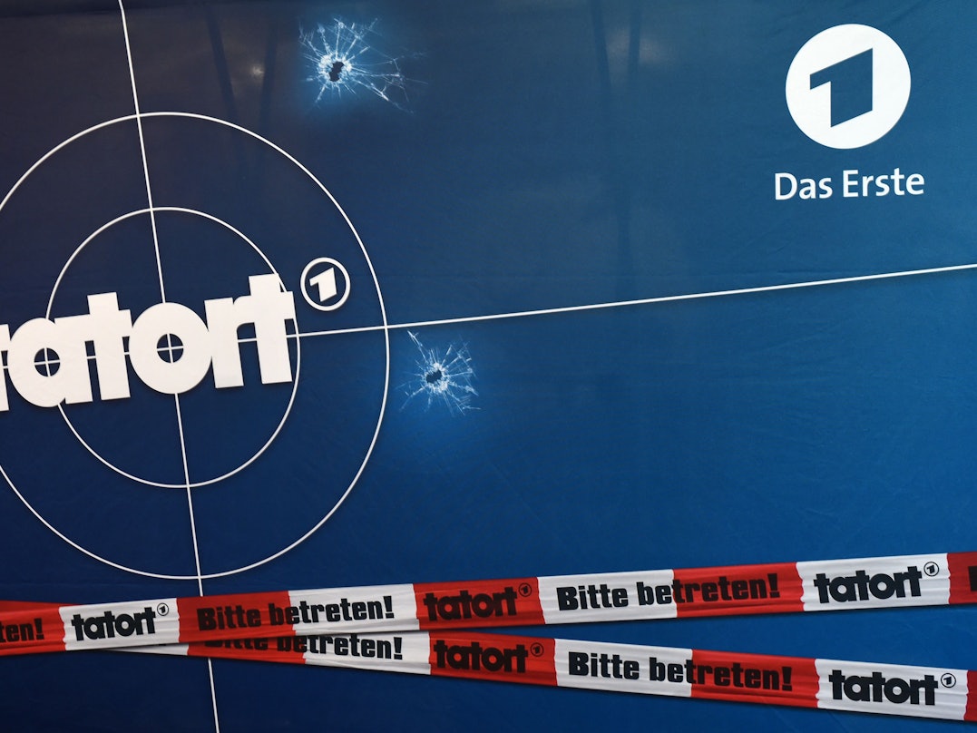 Auf einer Fotorückwand sind das Logo der ARD-Fernsehreihe „Tatort“.
