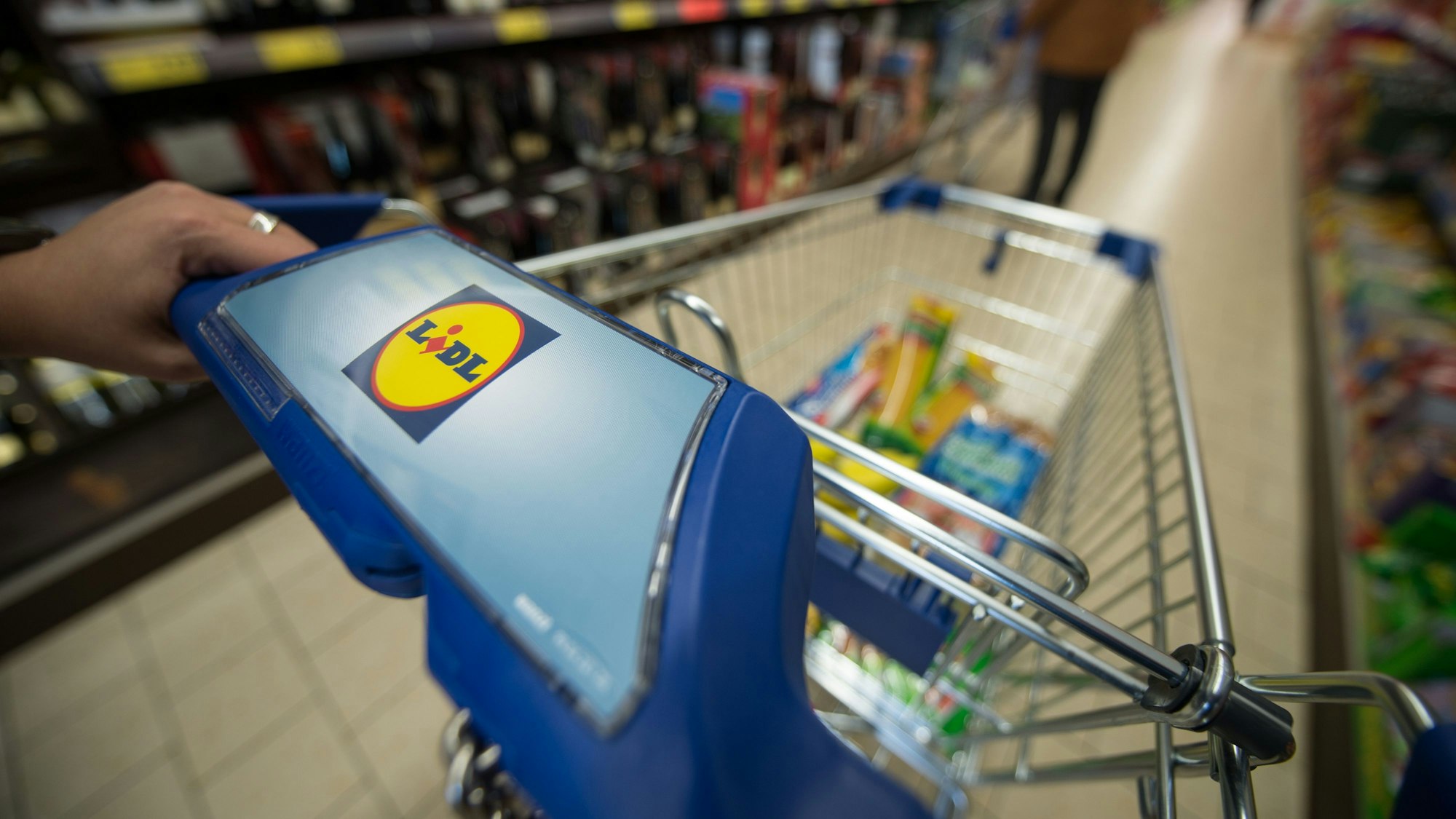 Eine Frau schiebt im März 2015 in Stuttgart (Baden-Württemberg) in einer Filiale des Lebensmitteldiscounters Lidl einen Einkaufswagen durch die Regalreihen.