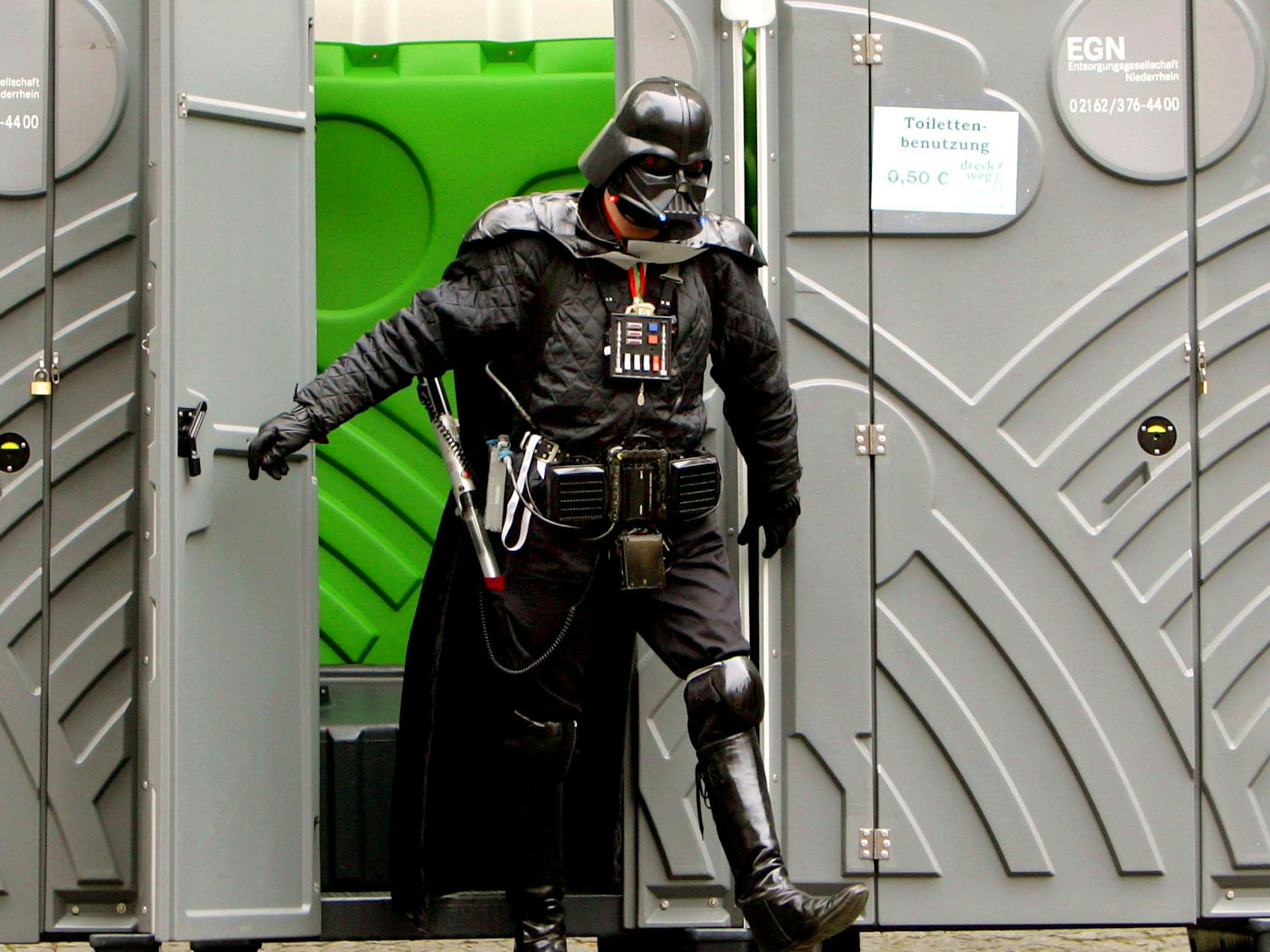 „Darth Vader“ verlässt auf dem Alter Markt in Köln eine mobile Toilette.