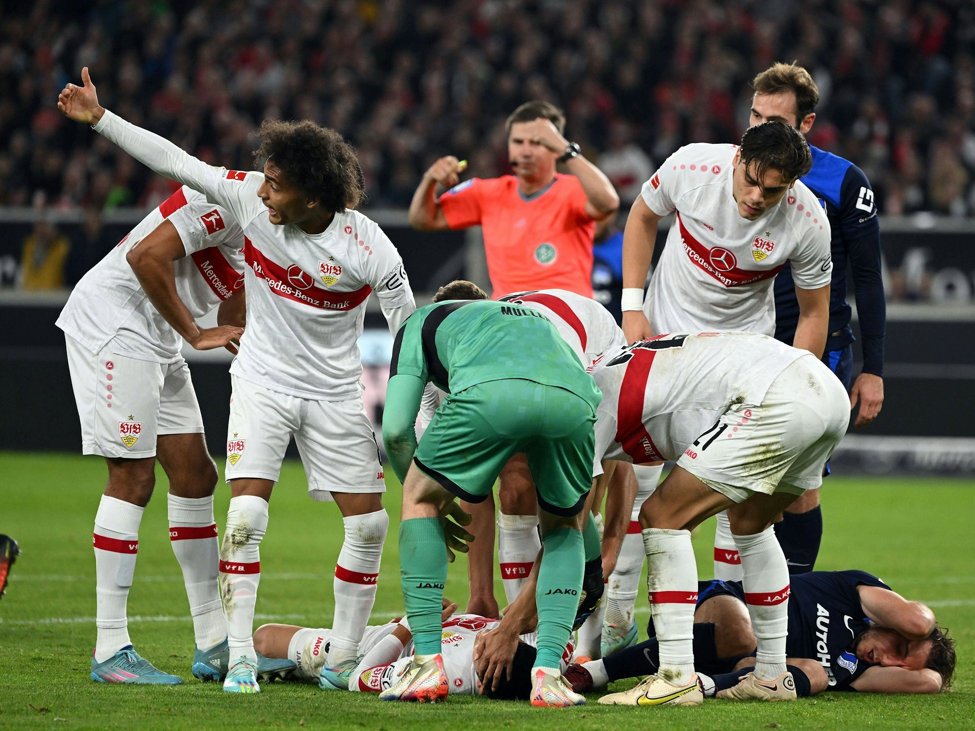 Wataru Endo (VfB Stuttgart) liegt auf dem Boden, die Mitspieler kümmern sich um ihn.