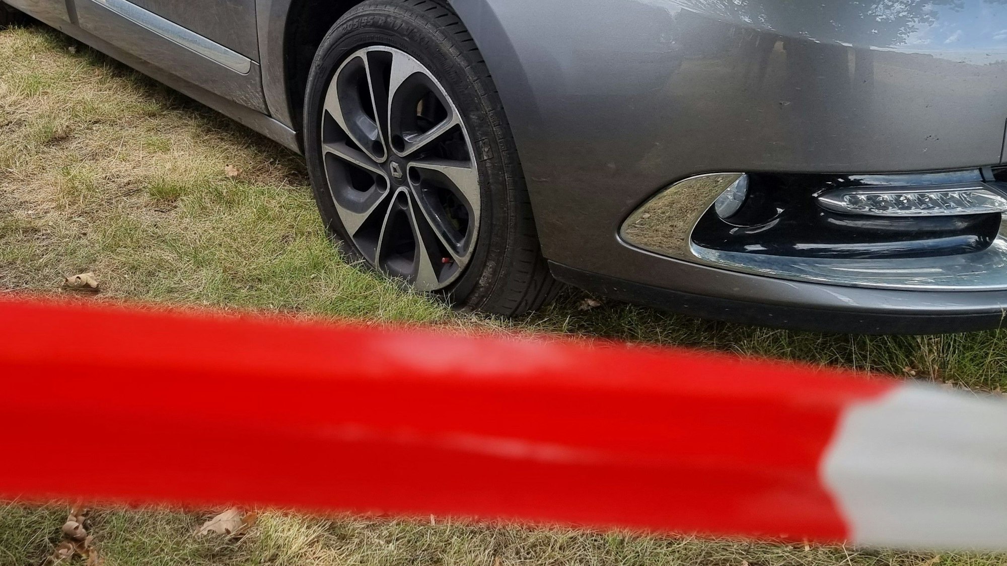 Autos mit zerstochenen Reifen stehen auf einer Rasenfläche.