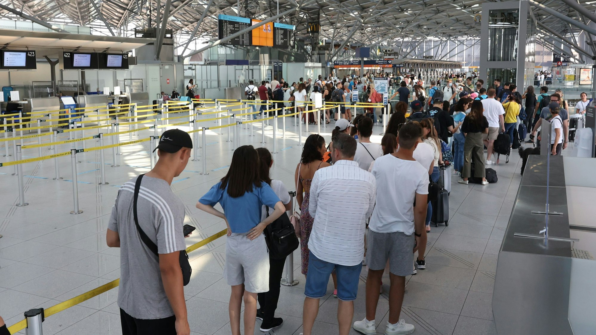 Lange Schlange am Flughafen Köln/Bonn. Reisende kommen mit Verspätung in den Urlaub.
