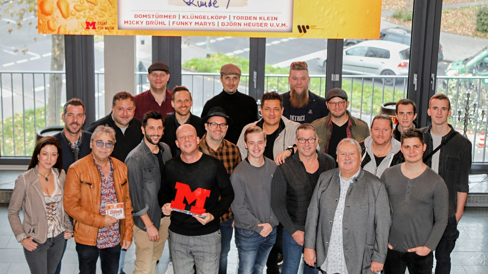 Label-Chef Manfred Rolef lacht mit allen anwesenden Künstlerinnen und Künstlern in die Kamera.