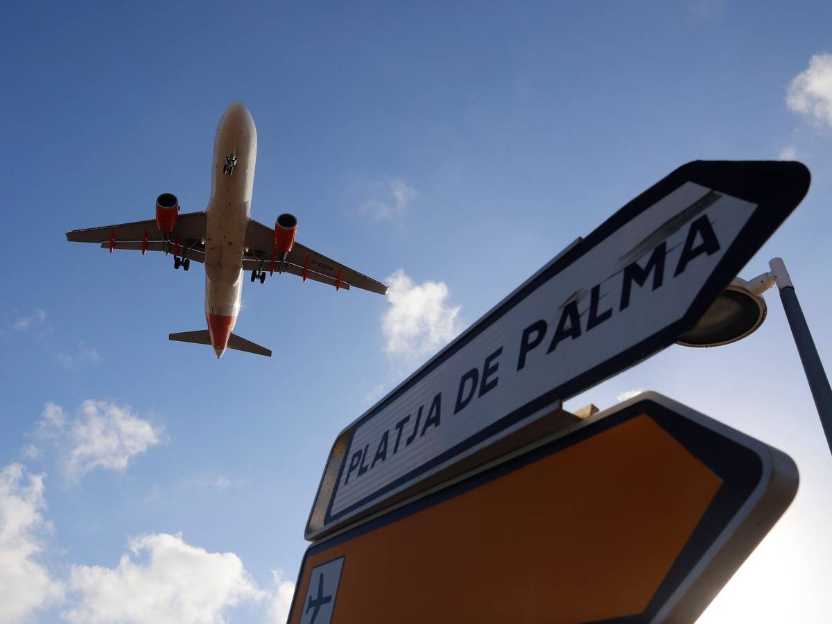 Ein Flugzeug überfliegt bei der Landung auf Mallorca ein Schild, das die Richtung nach Playa de Palma anzeigt.