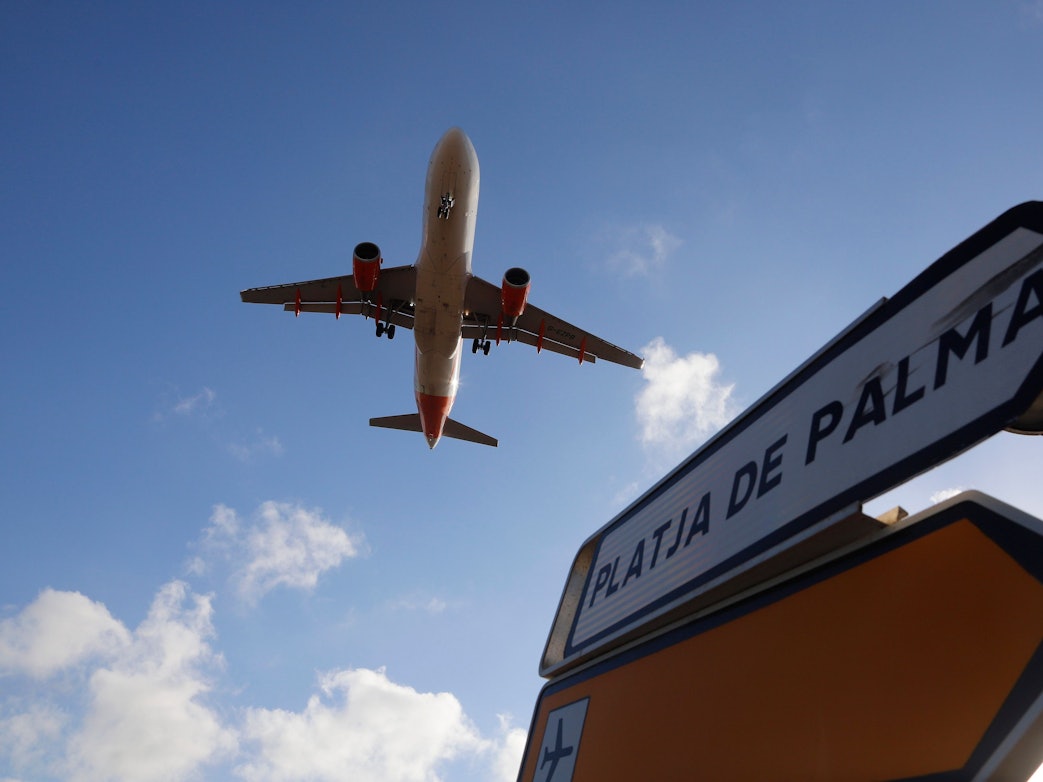 Ein Flugzeug überfliegt bei der Landung auf Mallorca ein Schild, das die Richtung nach Playa de Palma anzeigt.