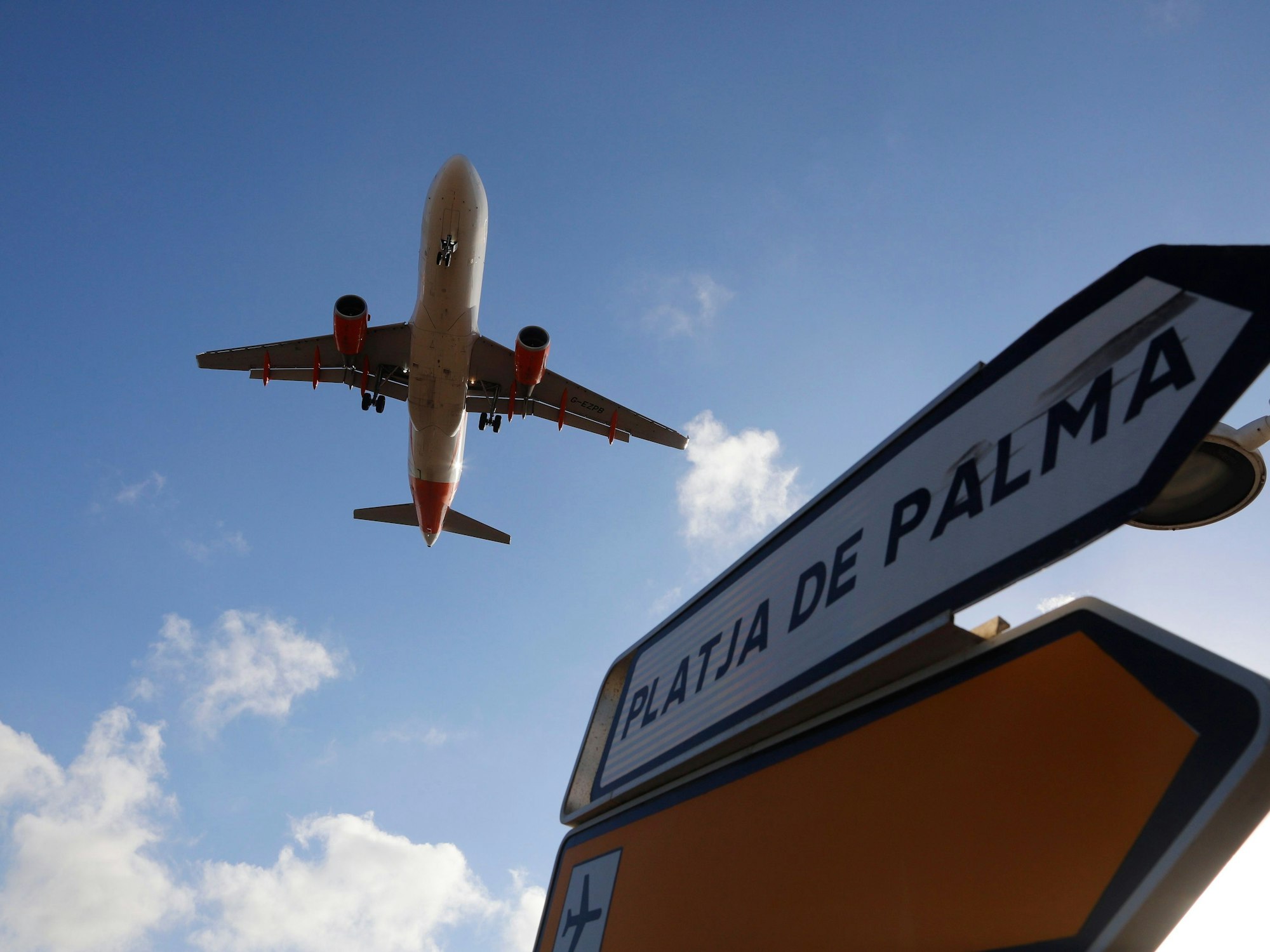 Ein Flugzeug überfliegt bei der Landung auf Mallorca ein Schild, das die Richtung nach Playa de Palma anzeigt.