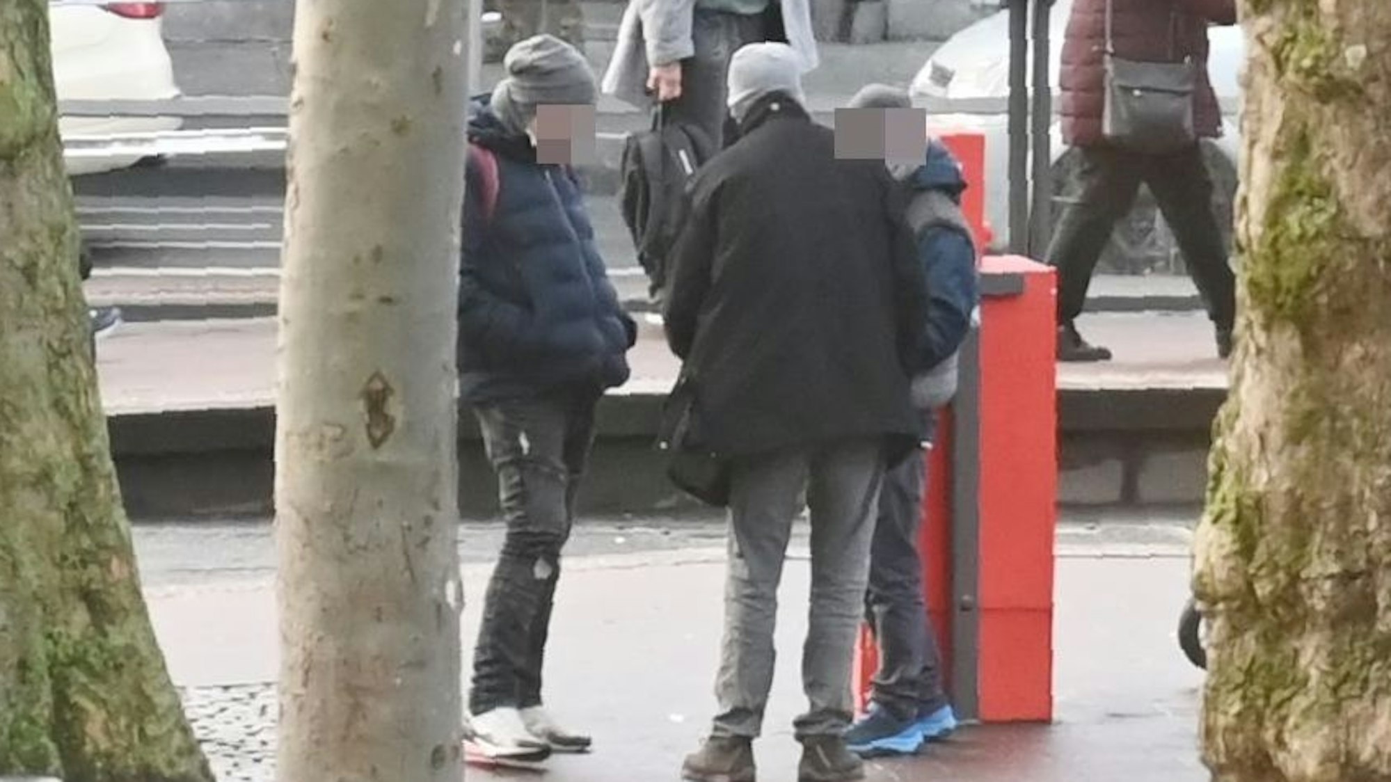 Mehrere Personen stehen am Neumarkt in Köln zusammen und verteilen Drogen unter sich.