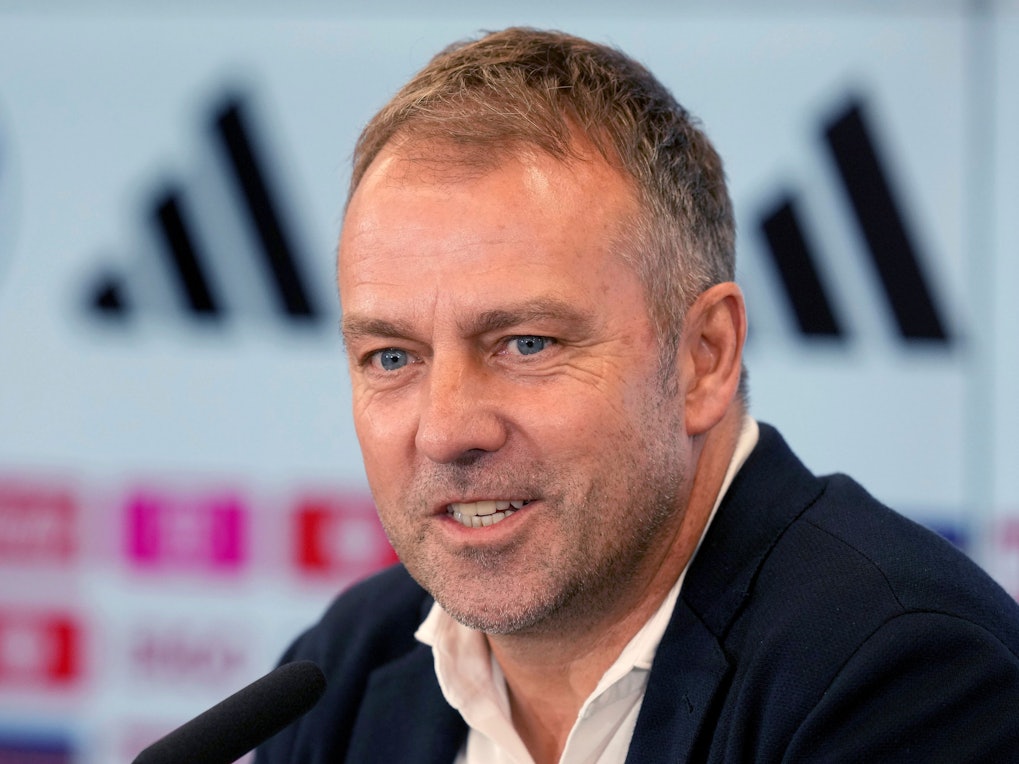 Hansi Flick sitzt bei der Verkündung seines DFB-Aufgebots für die WM 2022 in Katar am Rednerpult