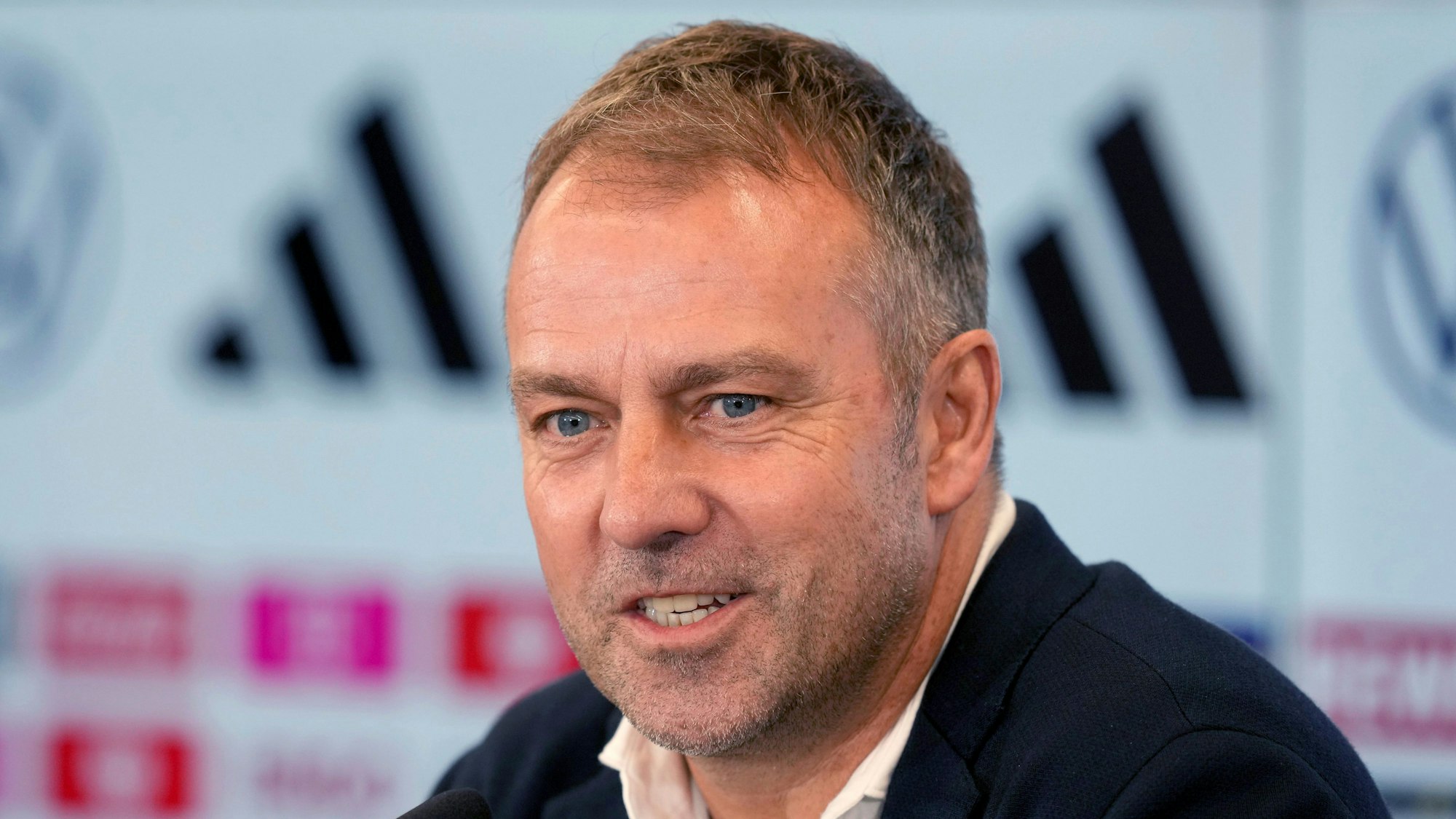 Hansi Flick sitzt bei der Verkündung seines DFB-Aufgebots für die WM 2022 in Katar am Rednerpult