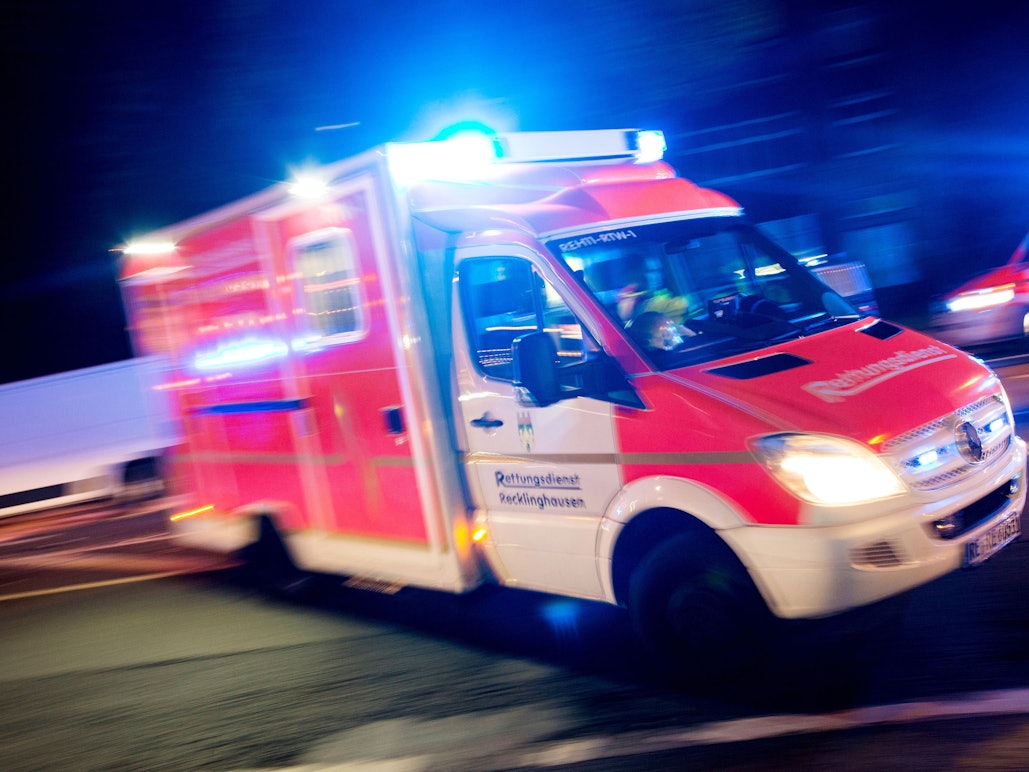 Ein Rettungswagen der Feuerwehr fährt mit Blaulicht durch eine Straße.