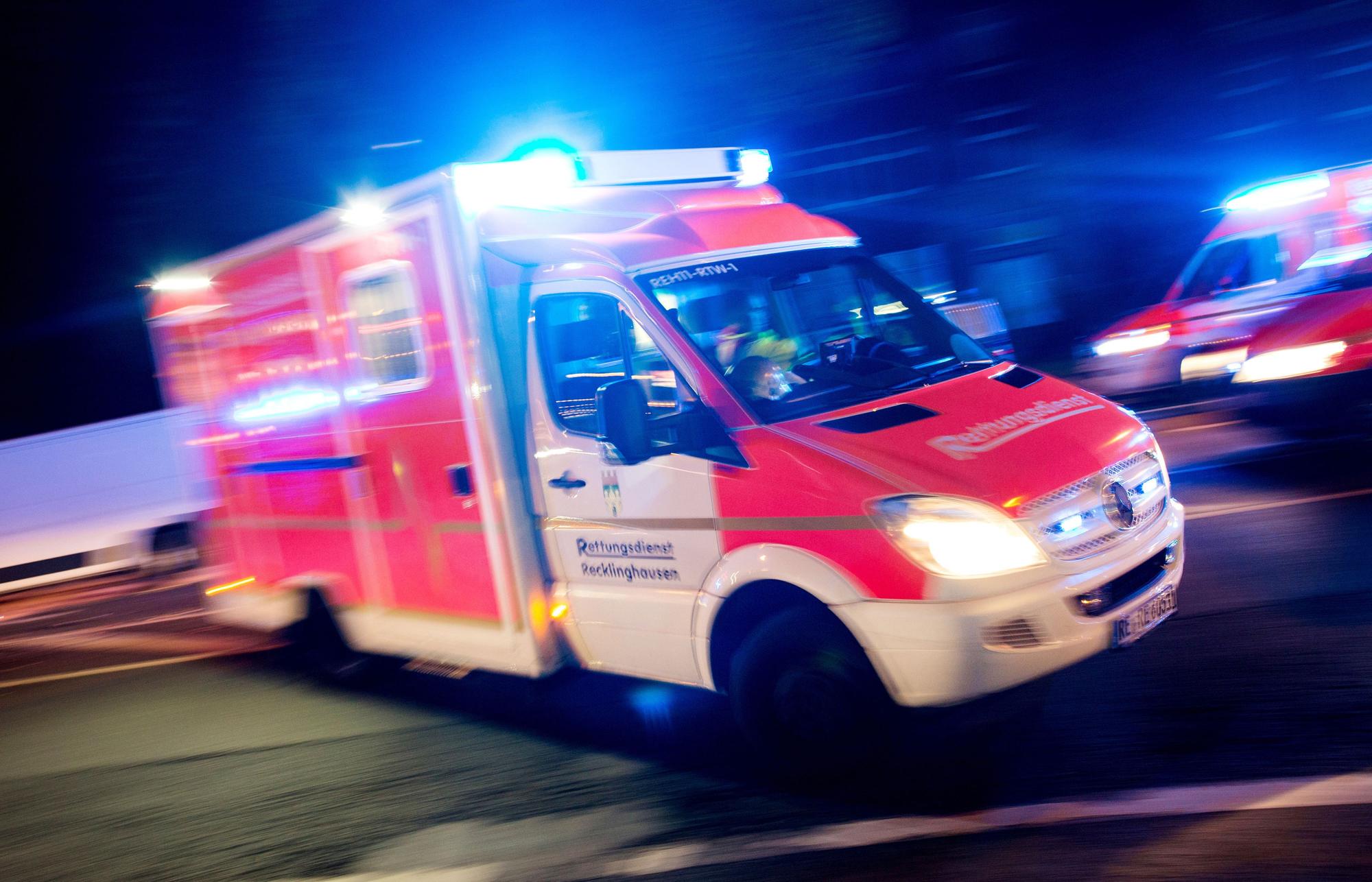 Ein Rettungswagen der Feuerwehr fährt mit Blaulicht durch eine Straße.