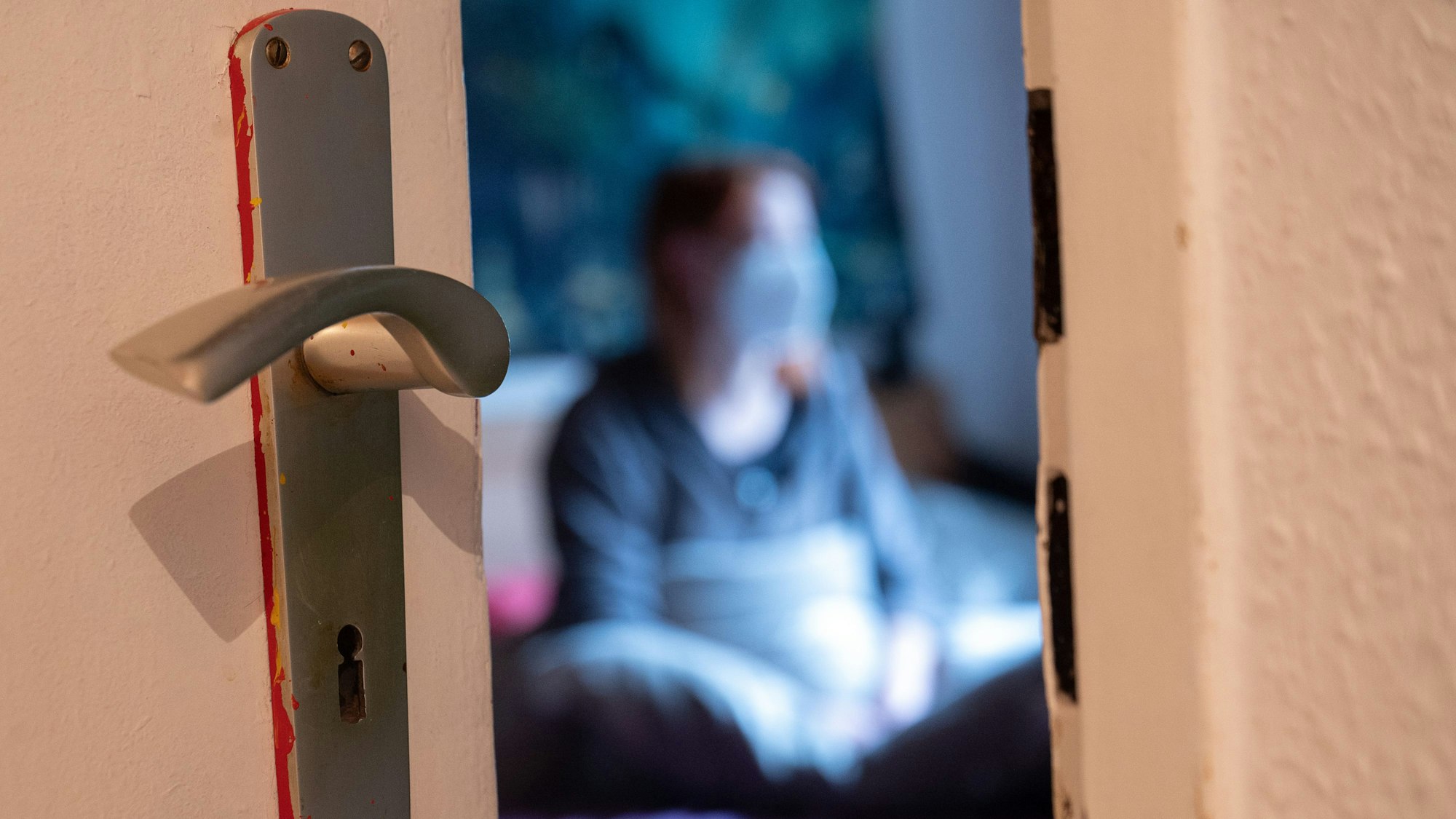 Eine Frau sitzt während der Isolation nach einem positiven Corona-PCR-Test auf ihrem Bett.