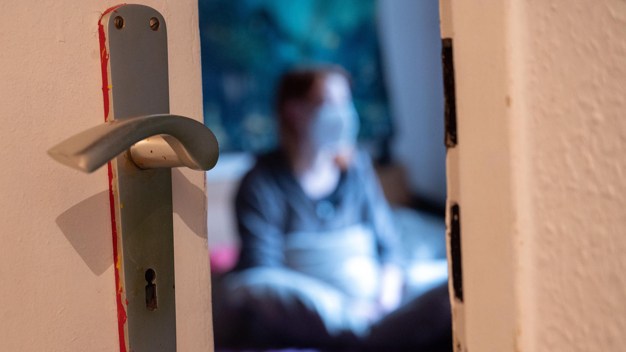 Eine Frau sitzt während der Isolation nach einem positiven Corona-PCR-Test auf ihrem Bett.