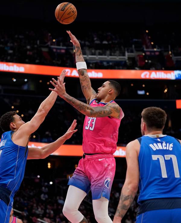 Washington Wizards Kyle Kuzma (m.) springt hoch, um einen Treffer zu erzielen, Mavericks Spencer Dinwiddie versucht ihn daran zu hindern.
