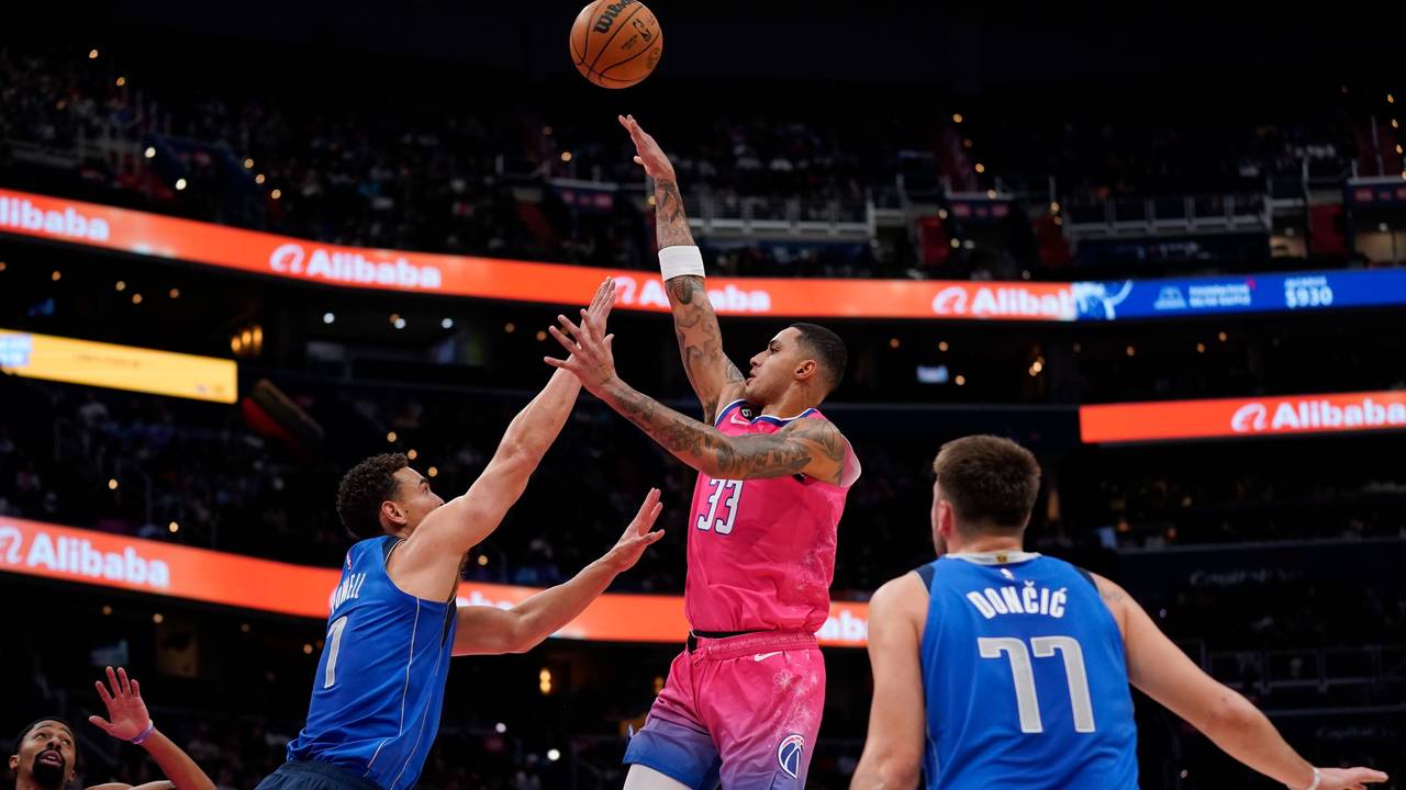 Washington Wizards Kyle Kuzma (m.) springt hoch, um einen Treffer zu erzielen, Mavericks Spencer Dinwiddie versucht ihn daran zu hindern.