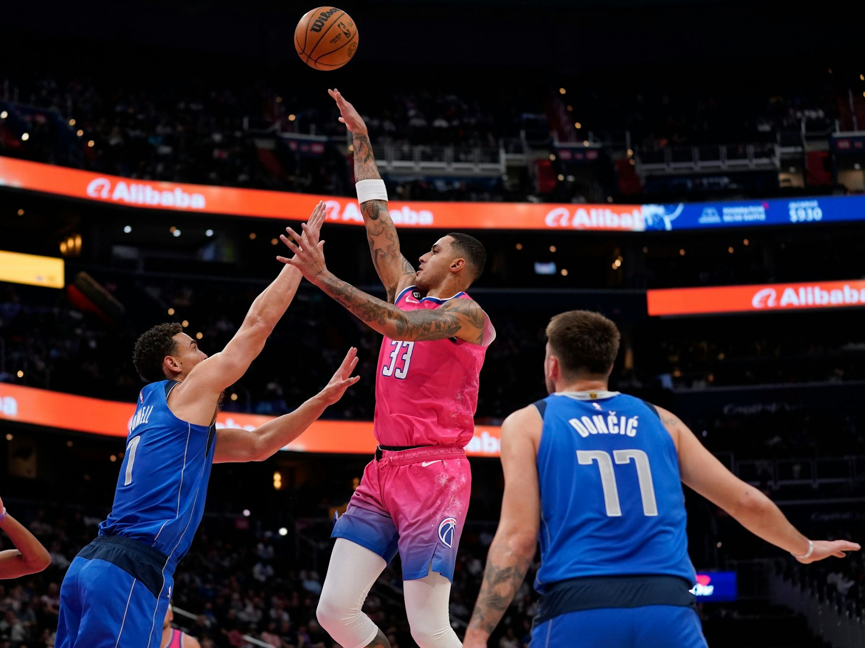 Washington Wizards Kyle Kuzma (m.) springt hoch, um einen Treffer zu erzielen, Mavericks Spencer Dinwiddie versucht ihn daran zu hindern.