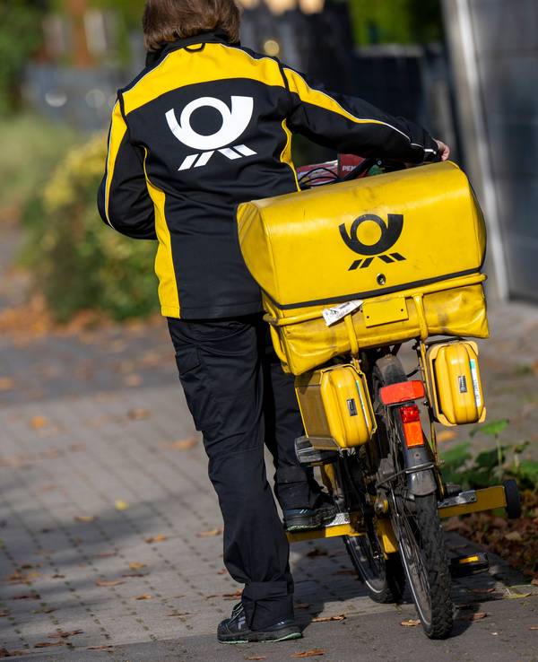 Eine Briefträgerin der Deutschen Post steigt auf ihr Postfahrrad. Die Deutsche Post hat bei der Zustellung von Briefen erhebliche Probleme eingeräumt.