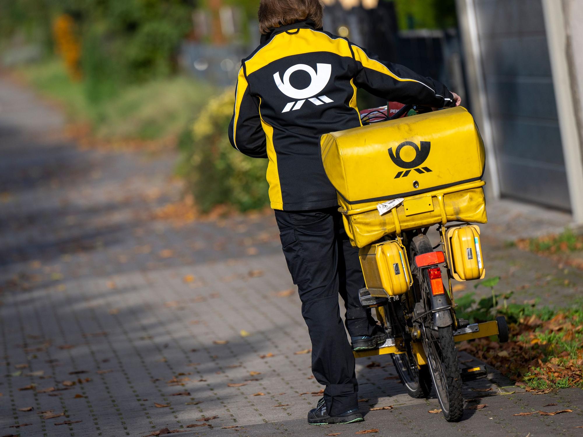 Eine Briefträgerin der Deutschen Post steigt auf ihr Postfahrrad. Die Deutsche Post hat bei der Zustellung von Briefen erhebliche Probleme eingeräumt.