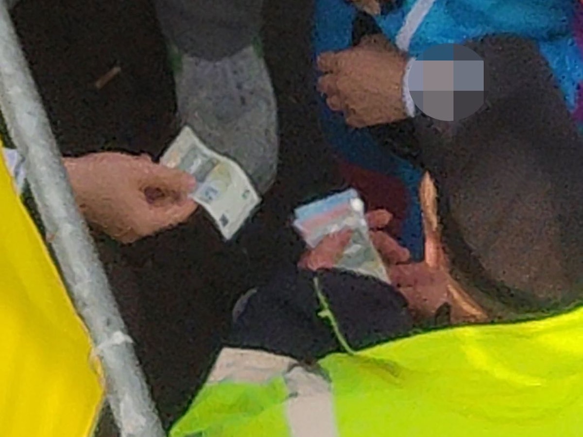 Ein Ordner nimmt einen Fünf-Euro-Schein von einem Feiernden entgegen. Die Szene wurde am 11.11.2022 am Ausgangsbereich der Zülpicher Straße aufgenommen.