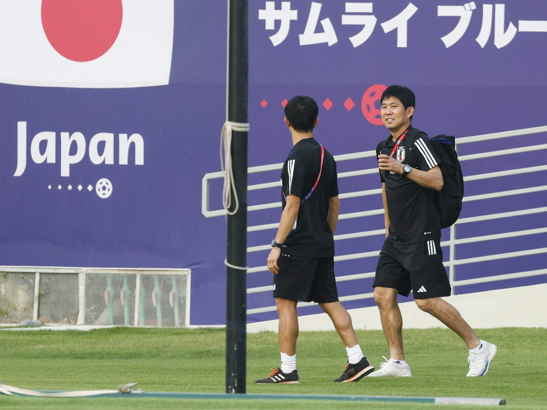 Japans Fußballtrainer Hajime Moriyasu (r.) prüft den Zustand des Spielfelds in der Trainingsanlage des Al Sadd Sports Club in Doha, die der Nationalmannschaft aus Japan während der Weltmeisterschaft als Basislager dienen wird.