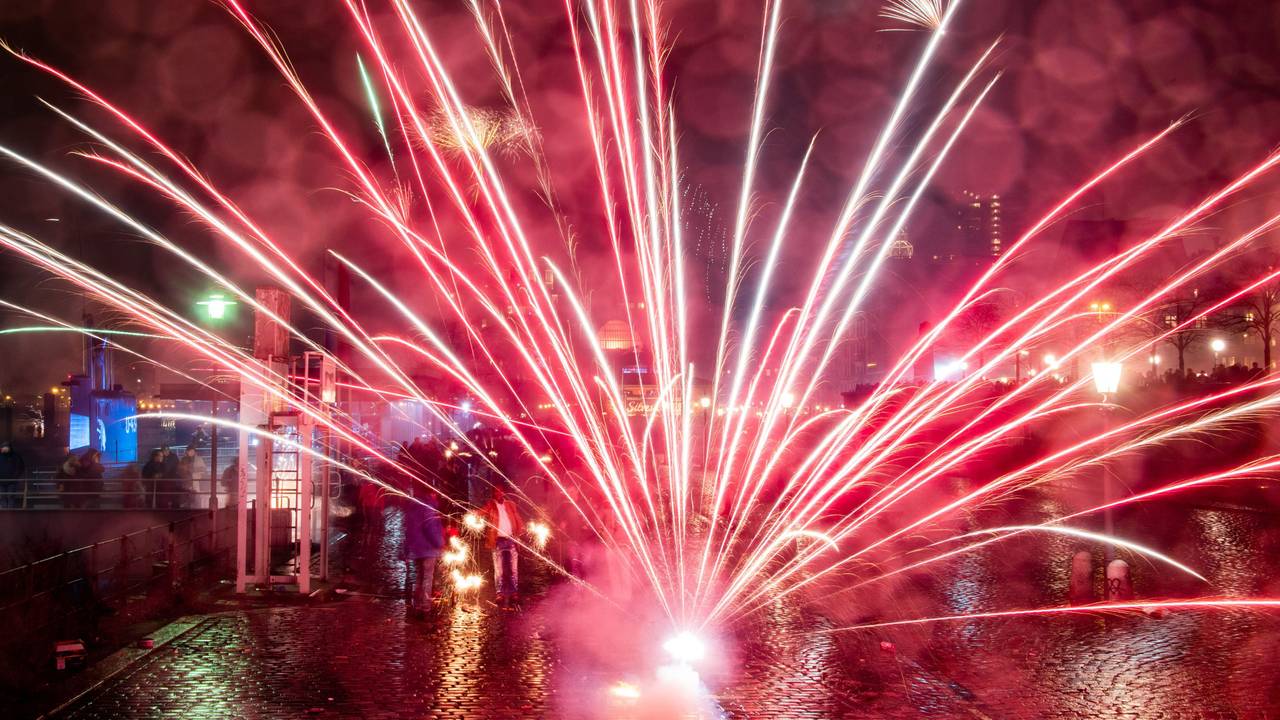 Menschen stehen auf einem Platz, auf dem Feuerwerk explodiert.