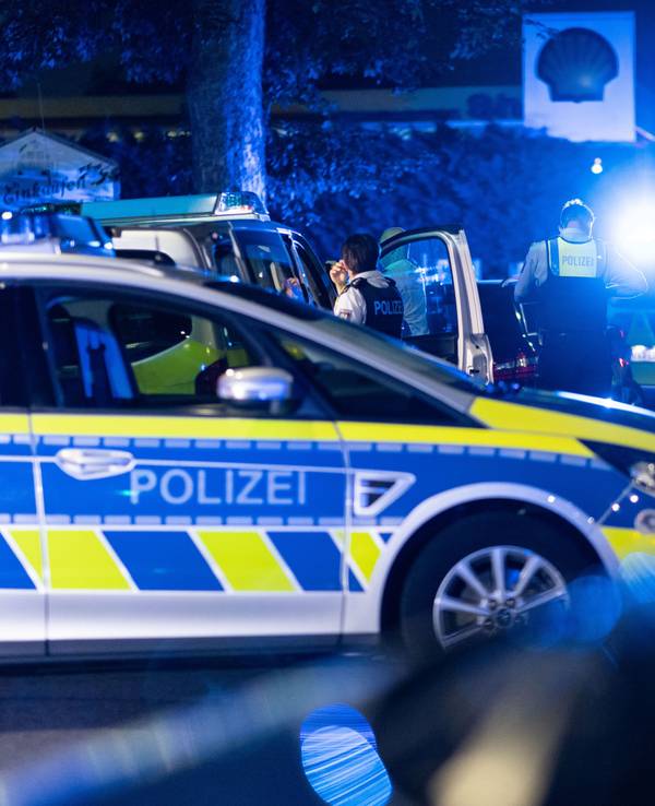 Einsatzkräfte der Polizei stehen vor einer Tankstelle.