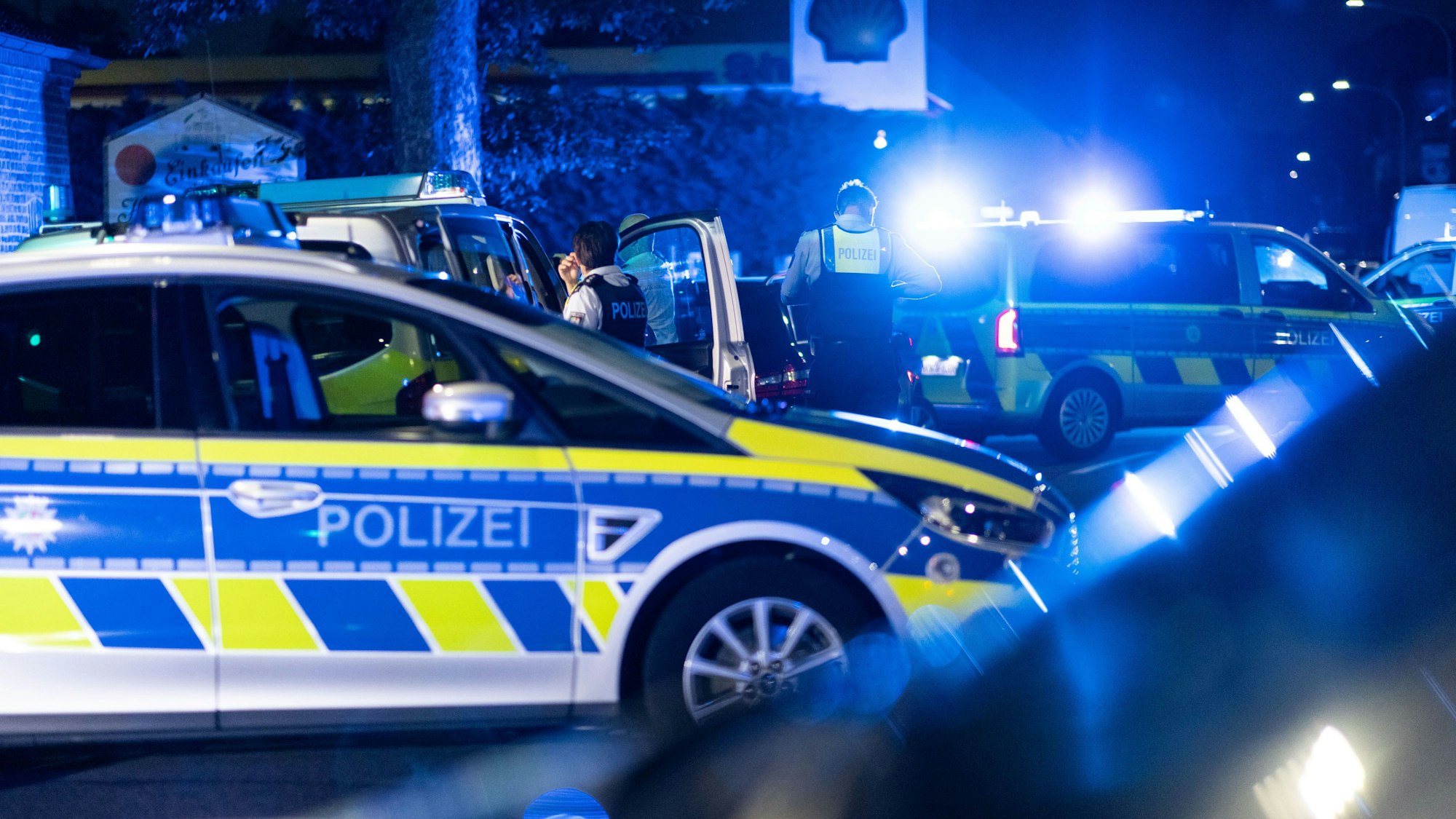 Einsatzkräfte der Polizei stehen vor einer Tankstelle.