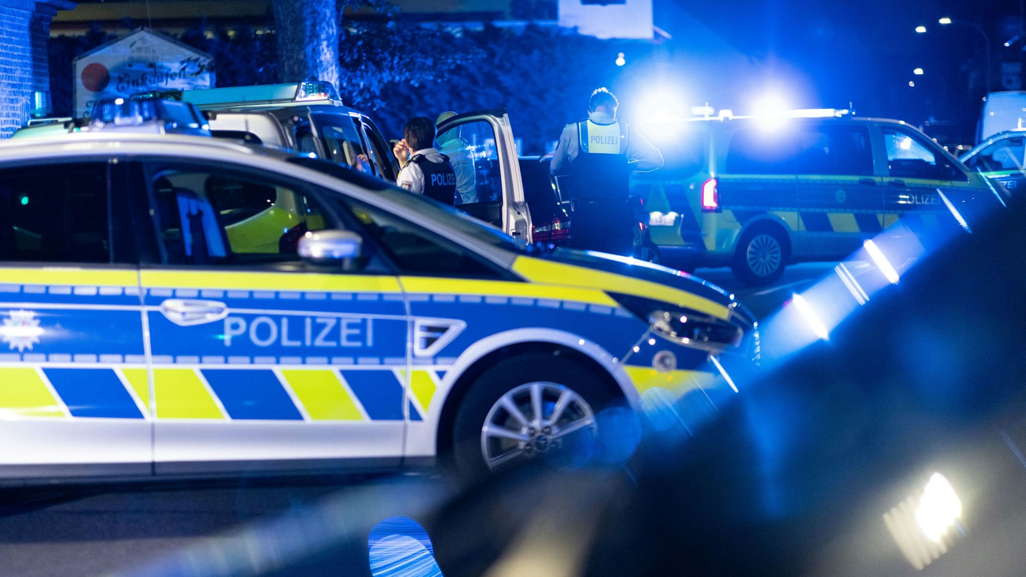 Einsatzkräfte der Polizei stehen vor einer Tankstelle.