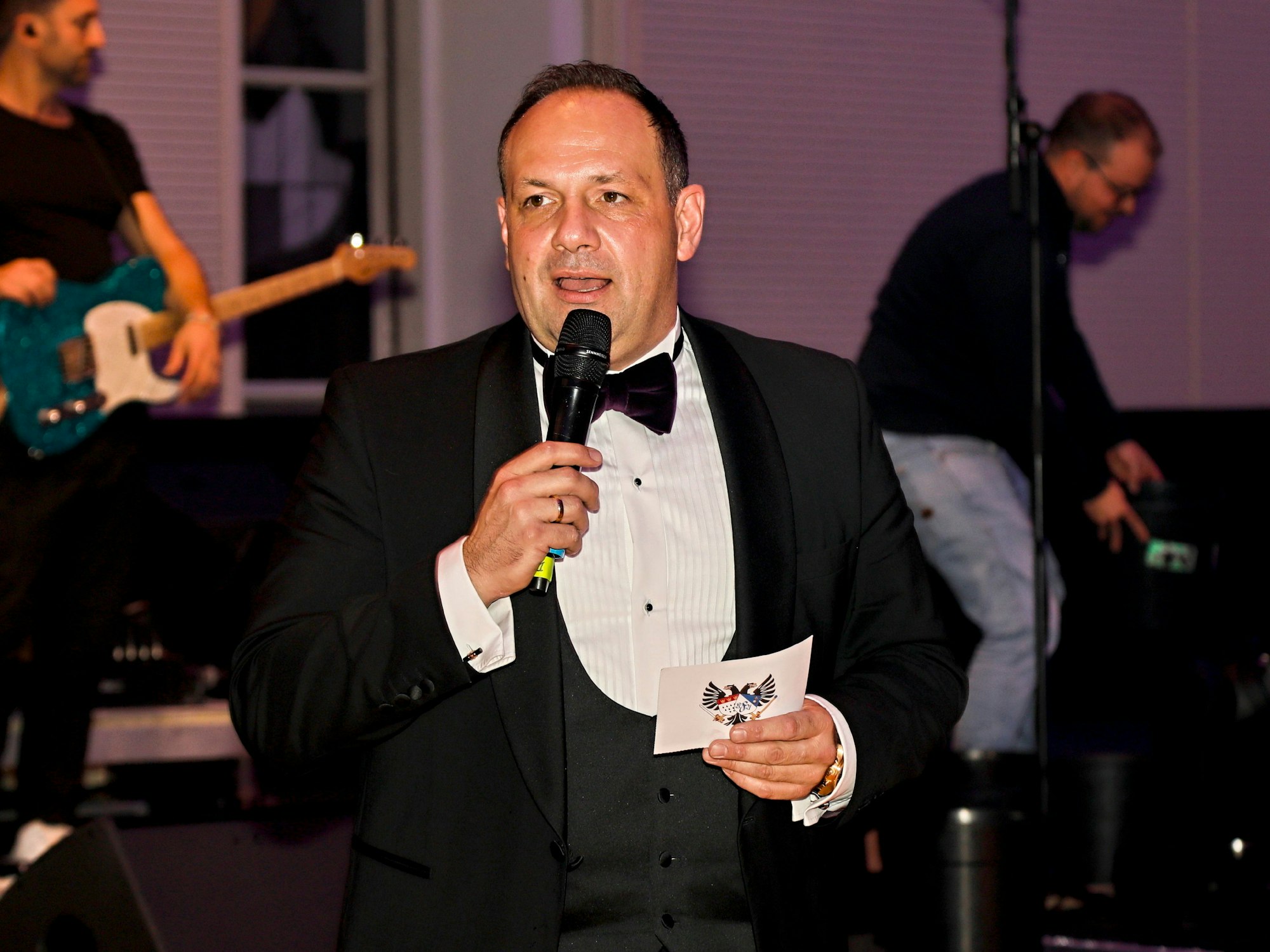 Björn Griesemann mit Anzug und Fliege als Moderator auf der Bühne der Blauen Funken.