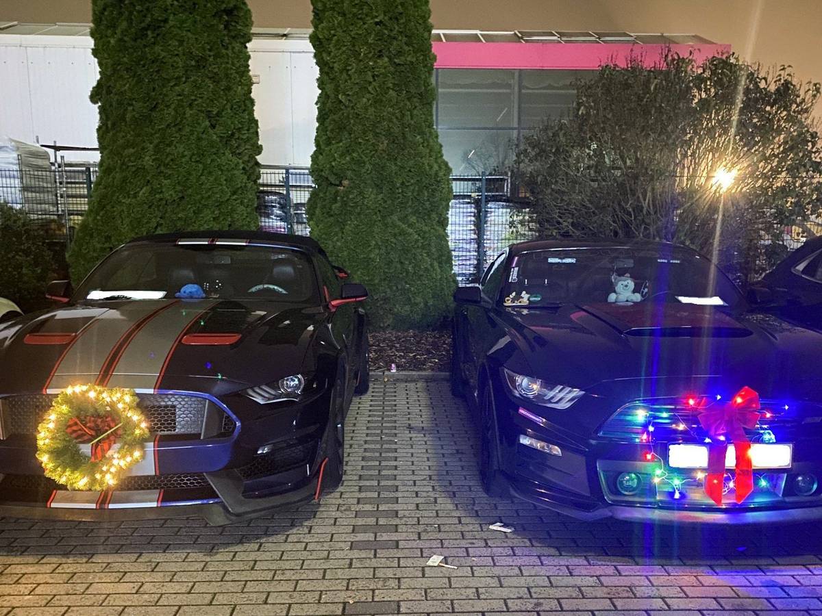 Sogenannte Muscle-Cars mit Weihnachtsdekoration sind auf einem Parkplatz in Ramstein-Miesenbach abgestellt.