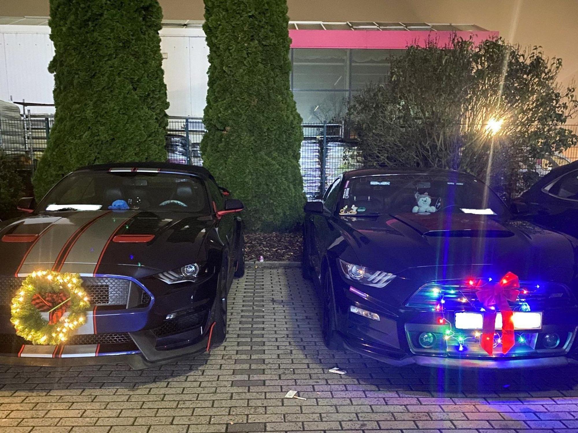 Sogenannte Muscle-Cars mit Weihnachtsdekoration sind auf einem Parkplatz in Ramstein-Miesenbach abgestellt.
