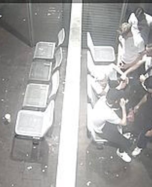 Vier junge Männer stehen vor zwei Männern, die sich gegen sie wehren wollen. Das Foto ist von oben aufgenommen und stammt aus einer Überwachungskamera.