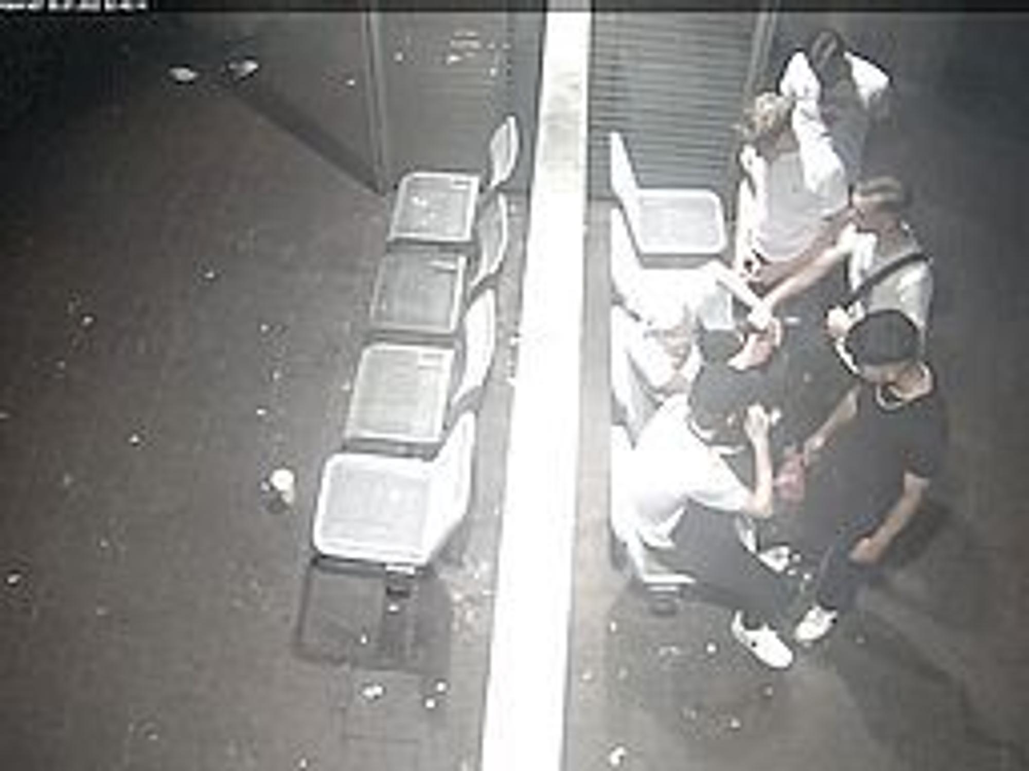 Vier junge Männer stehen vor zwei Männern, die sich gegen sie wehren wollen. Das Foto ist von oben aufgenommen und stammt aus einer Überwachungskamera.