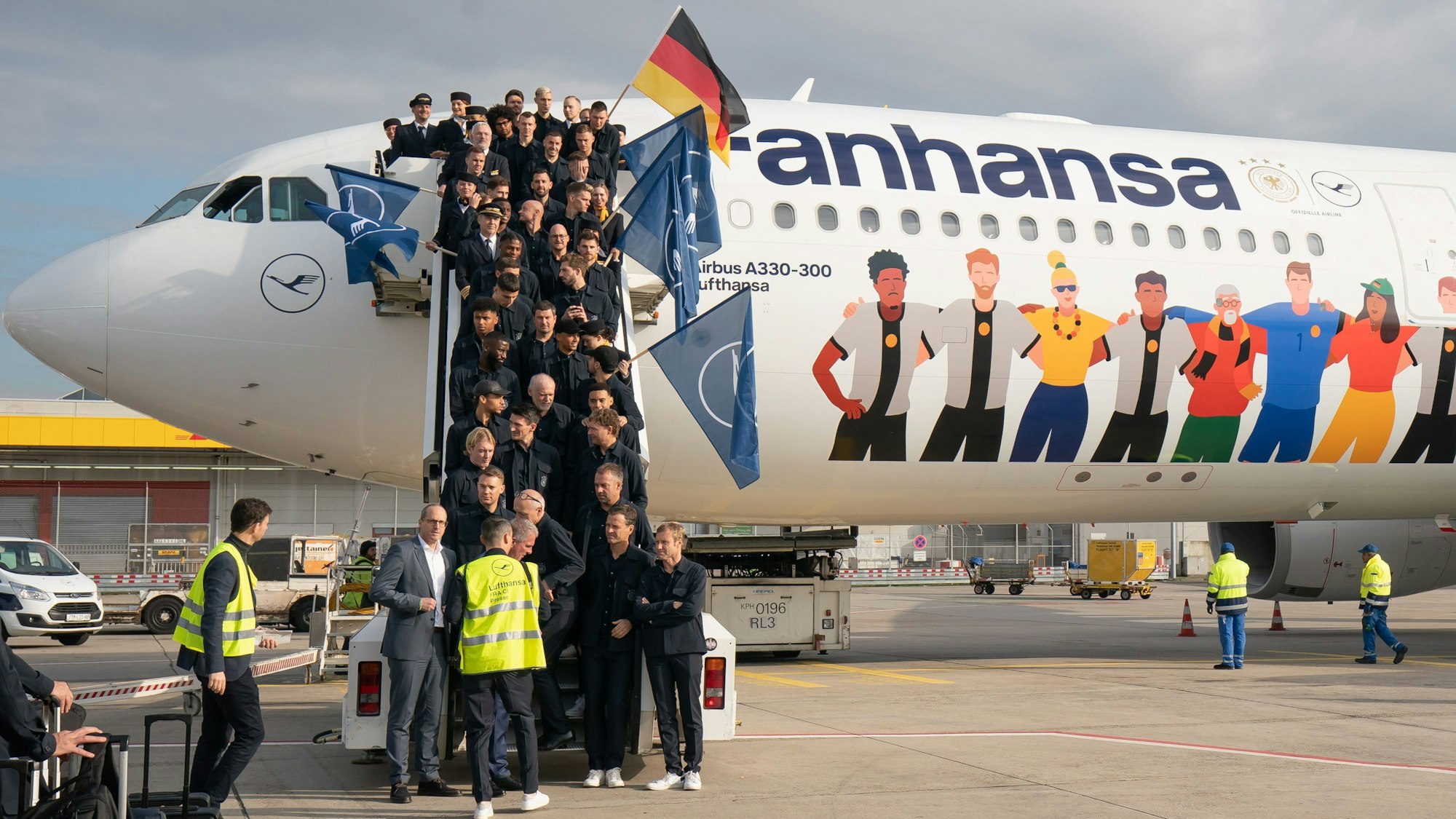 Die Nationalspieler stehen auf der Gangway am Flugzeug.