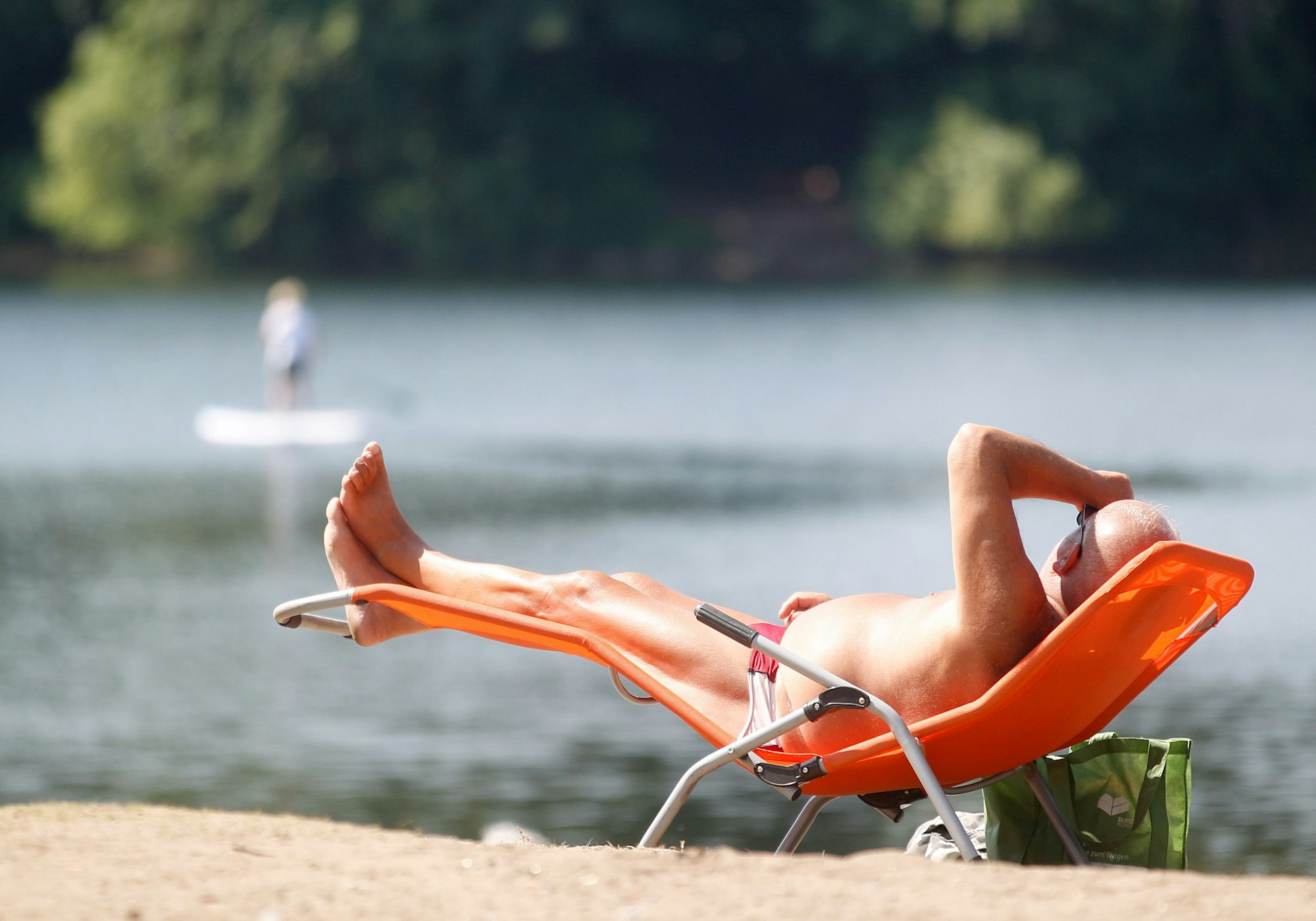 Ein Sonnenbad nimmt ein Badegast am Masurensee.