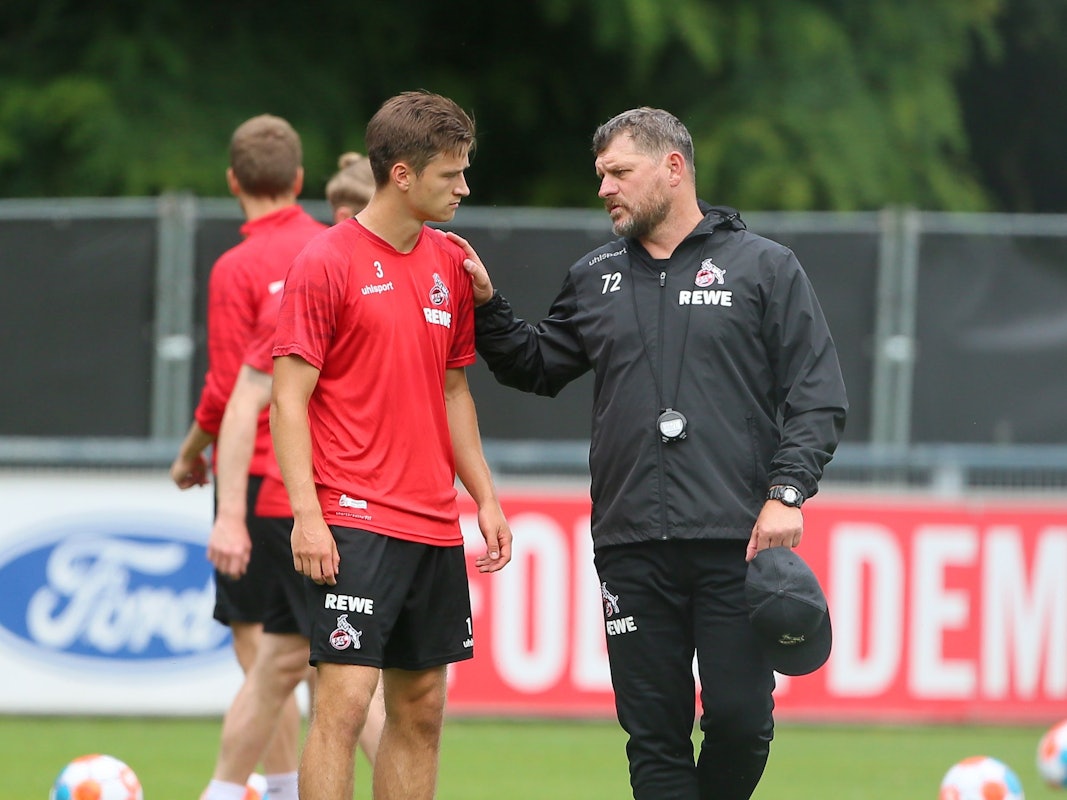 Steffen Baumgart spricht beim Training des 1. FC Köln mit Noah Katterbach.