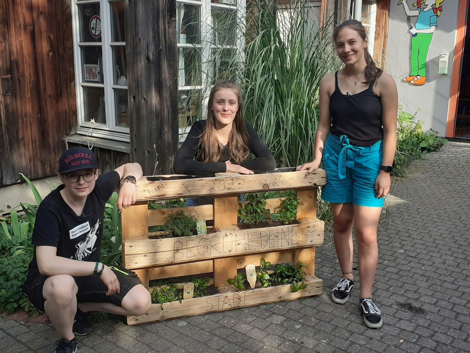 Die Kölner Schülerinnen Franziska, Rosa und Meike stehen vor einem ihrer Palettenbeete.