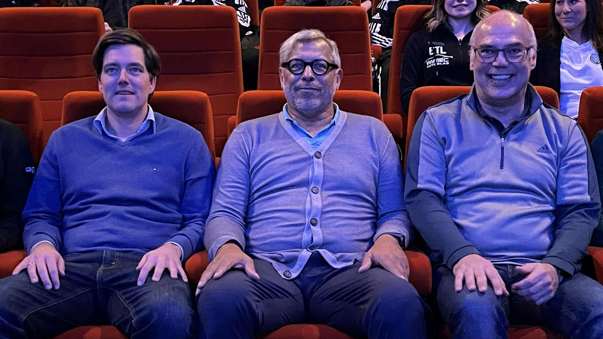 Jimmy Hartwig (M.) sitzt mit Viktoria-Geschäftsführer Axel Freisewinkel (l.) und FVM-Geschäftsführer Dirk Brennecke im Kino.