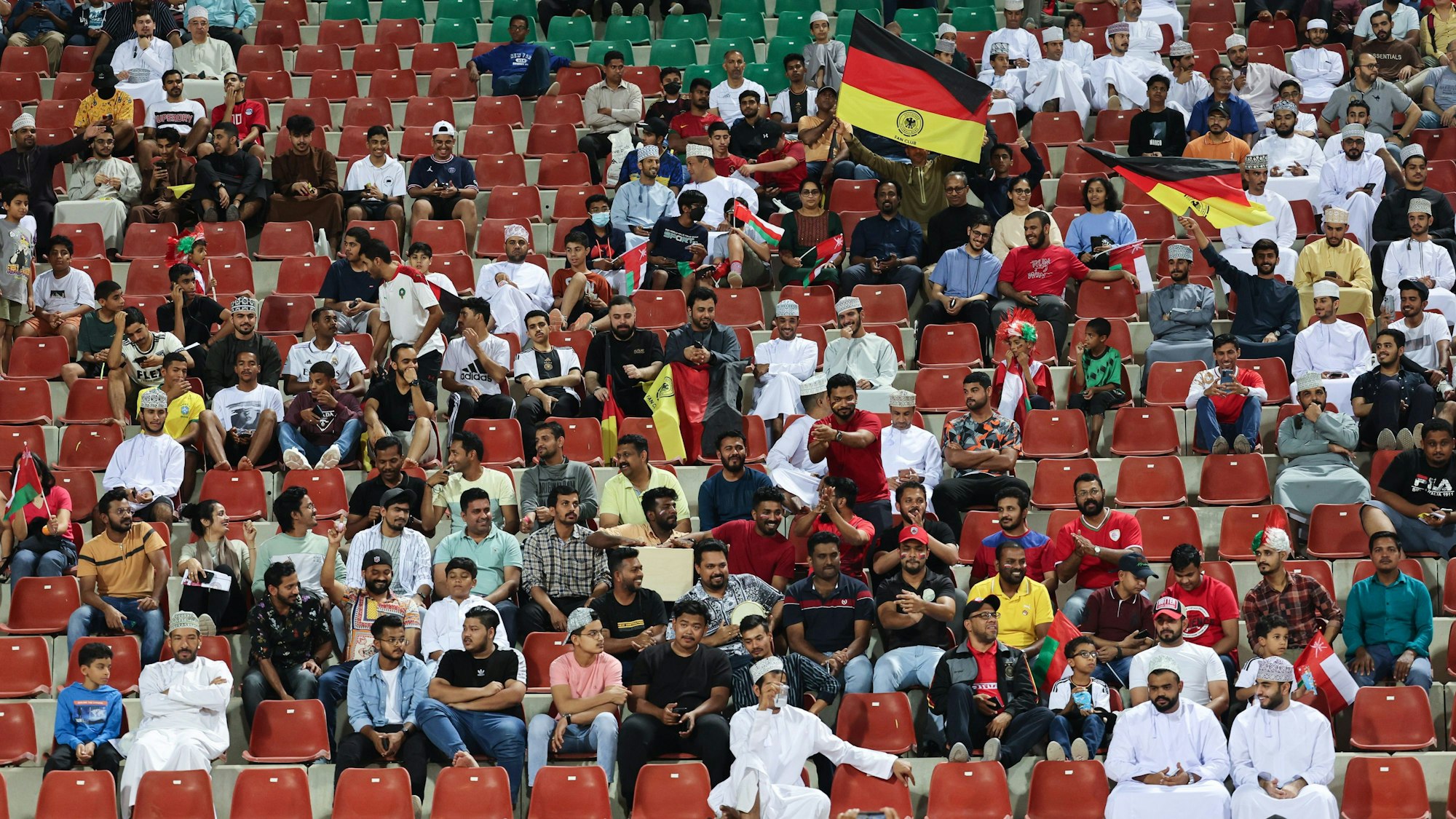 Fans sitzen beim Länderspiel der deutschen Nationalmannschaft gegen den Oman in Maskat auf der Tribüne.