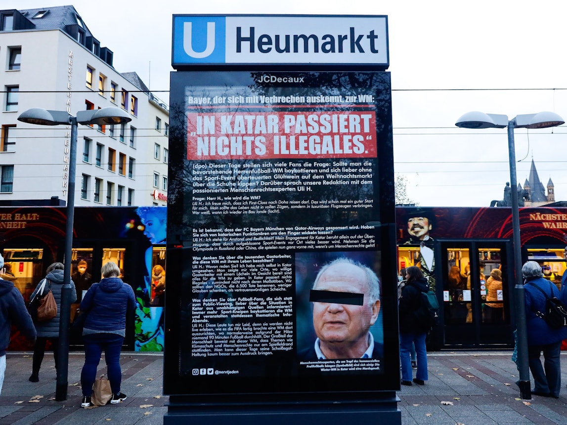 Plakat mit Foto und Aussagen von Uli Hoeneß am Neumarkt in Köln. Viele Menschen stehen drum herum.