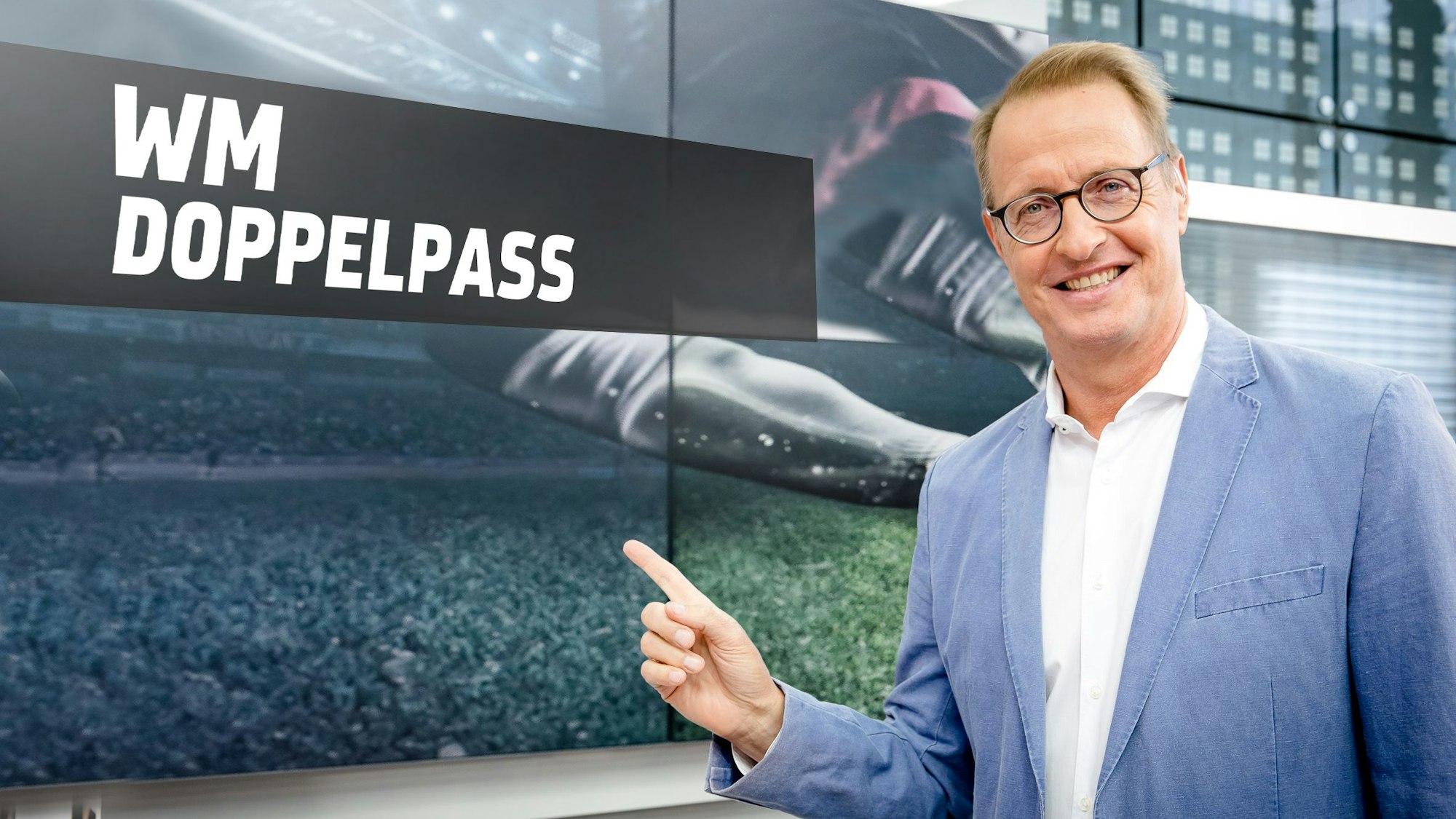 Moderator Florian König zeigt auf ein „WM-Doppelpass“-Schild.