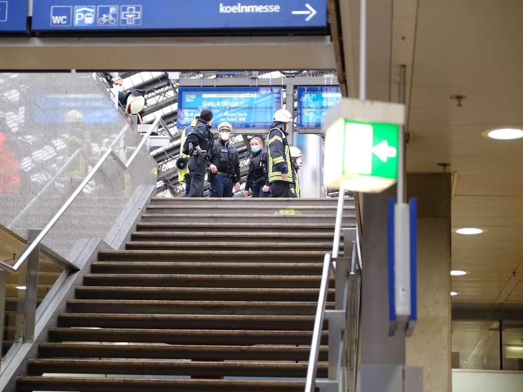 Rettungskräfte stehen am Kölner Hauptbahnhof und kümmern sich um einen Verletzten.