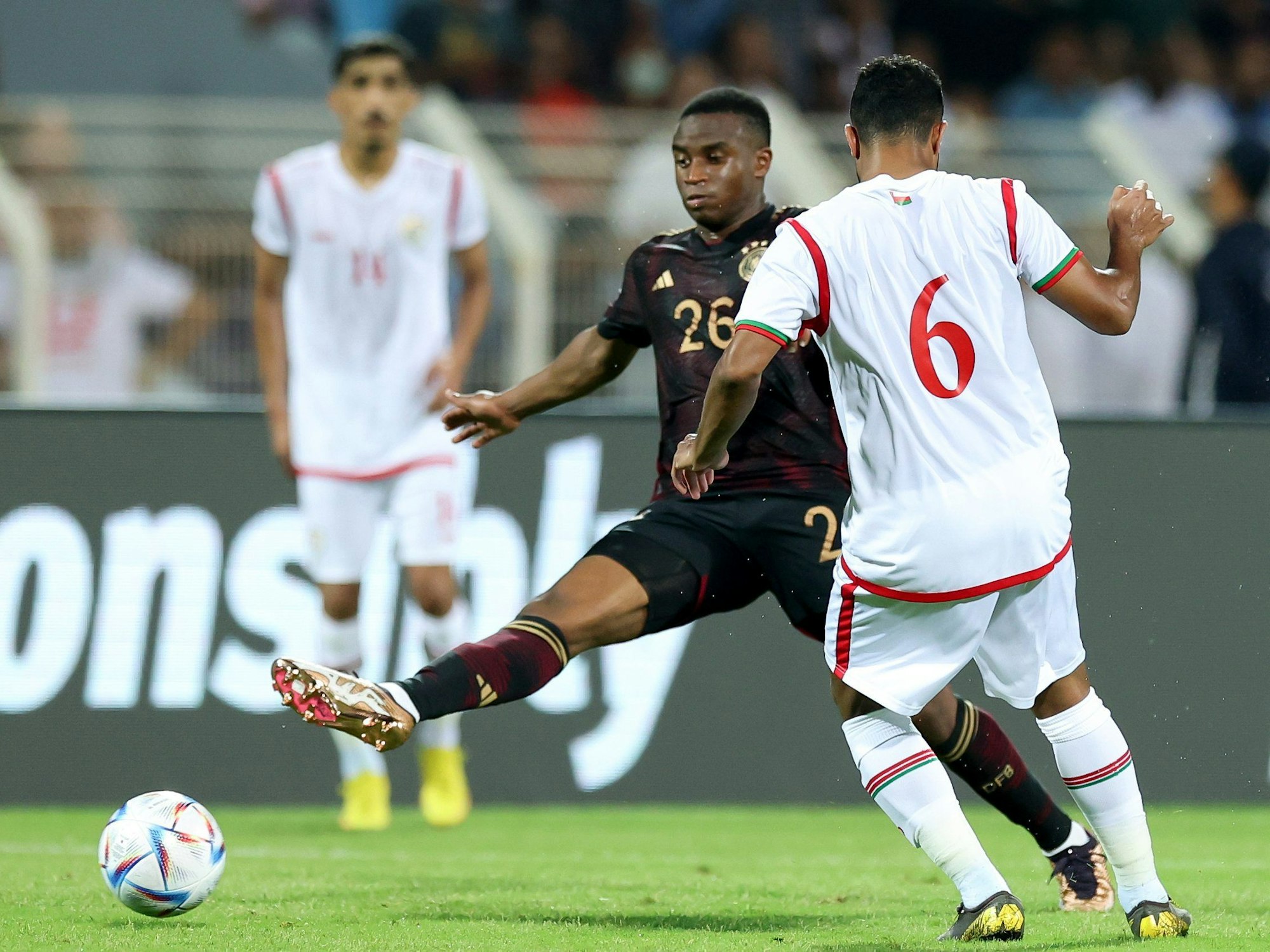 Deutschlands Youssoufa Moukoko (M) kämpft um den Ball mit Ahmed Al-Khamisi (r) aus dem Oman.
