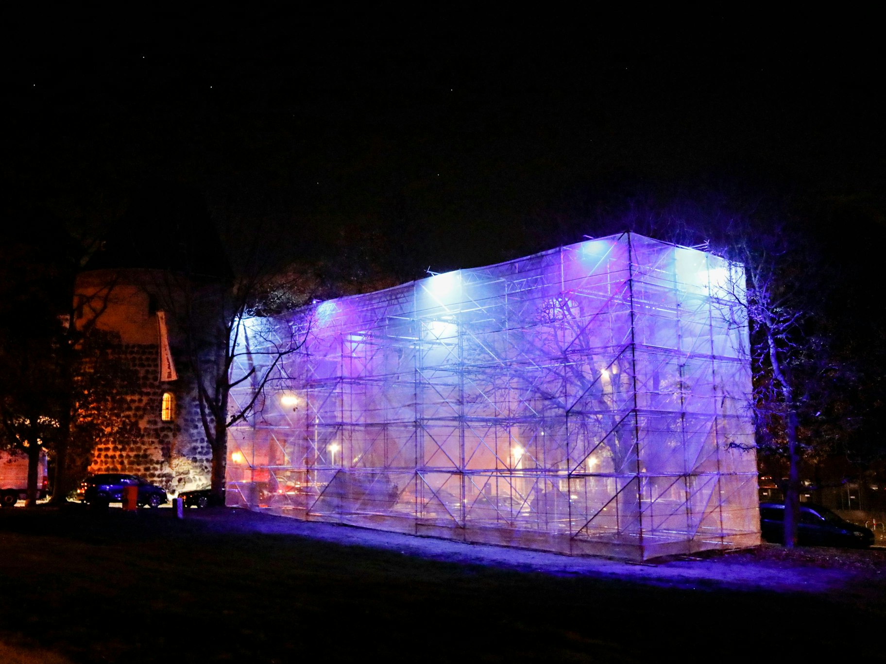 Gerüst steht in der Dunkelheit und wird von Licht ausgeleuchtet. Hier wollen die Blauen Funken den Sachsenturm in Köln ausbauen.