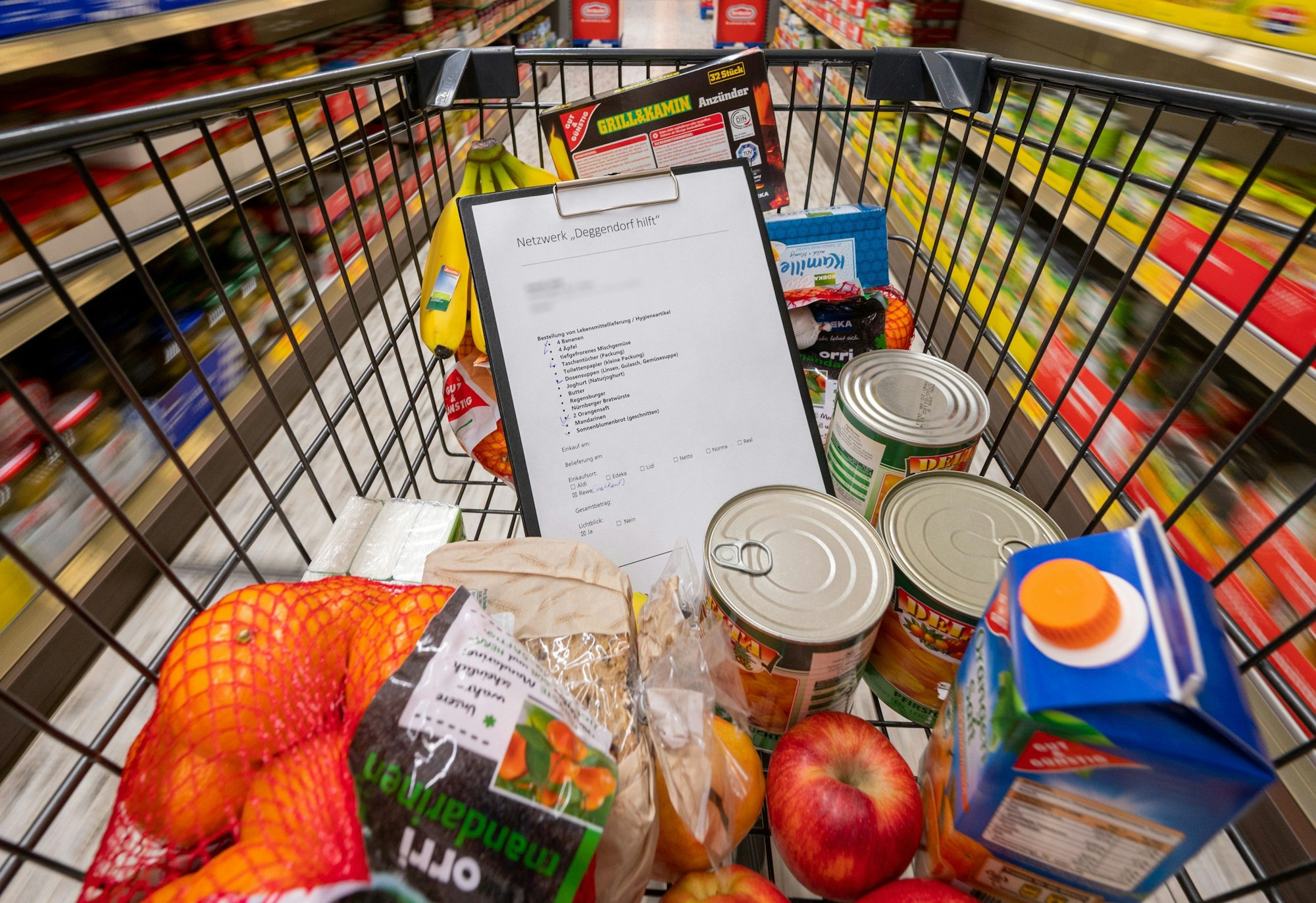 Nach einem Preisvergleich mit anderen Supermärkten schimpft eine Kundin gegen Aldi. Unser Foto zeigt einen Einkaufswagen mit einer Preisliste und verschiedenen Produkten.